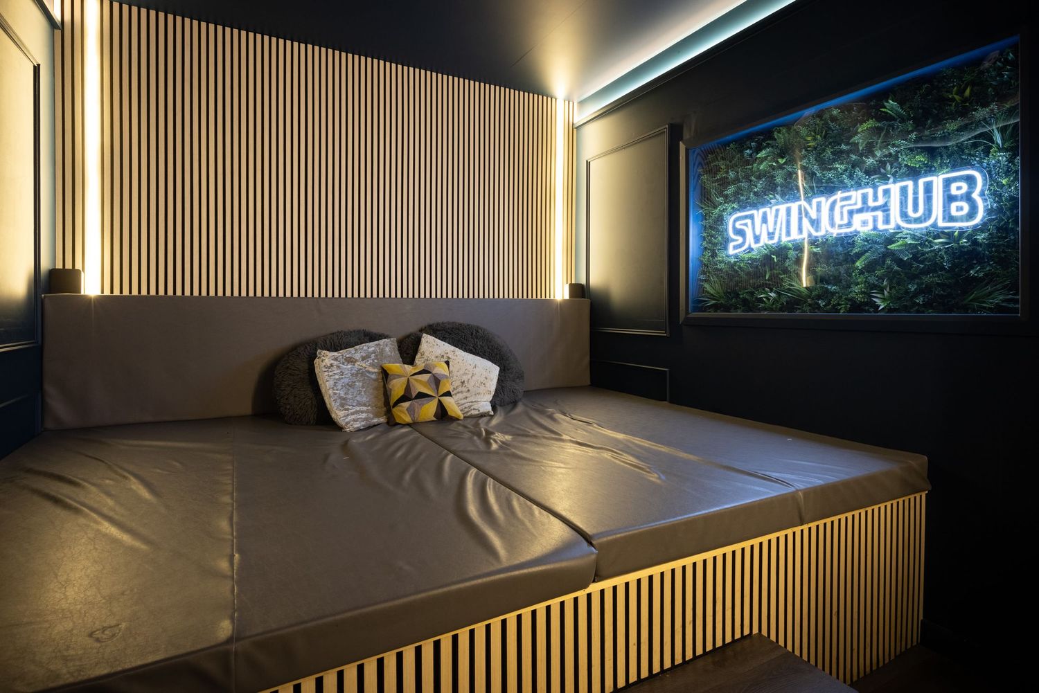 SwingHub room with wooden slat panels and warm lighting at Penthouse Playrooms Dunstable, creating a cosy adult club interior space
