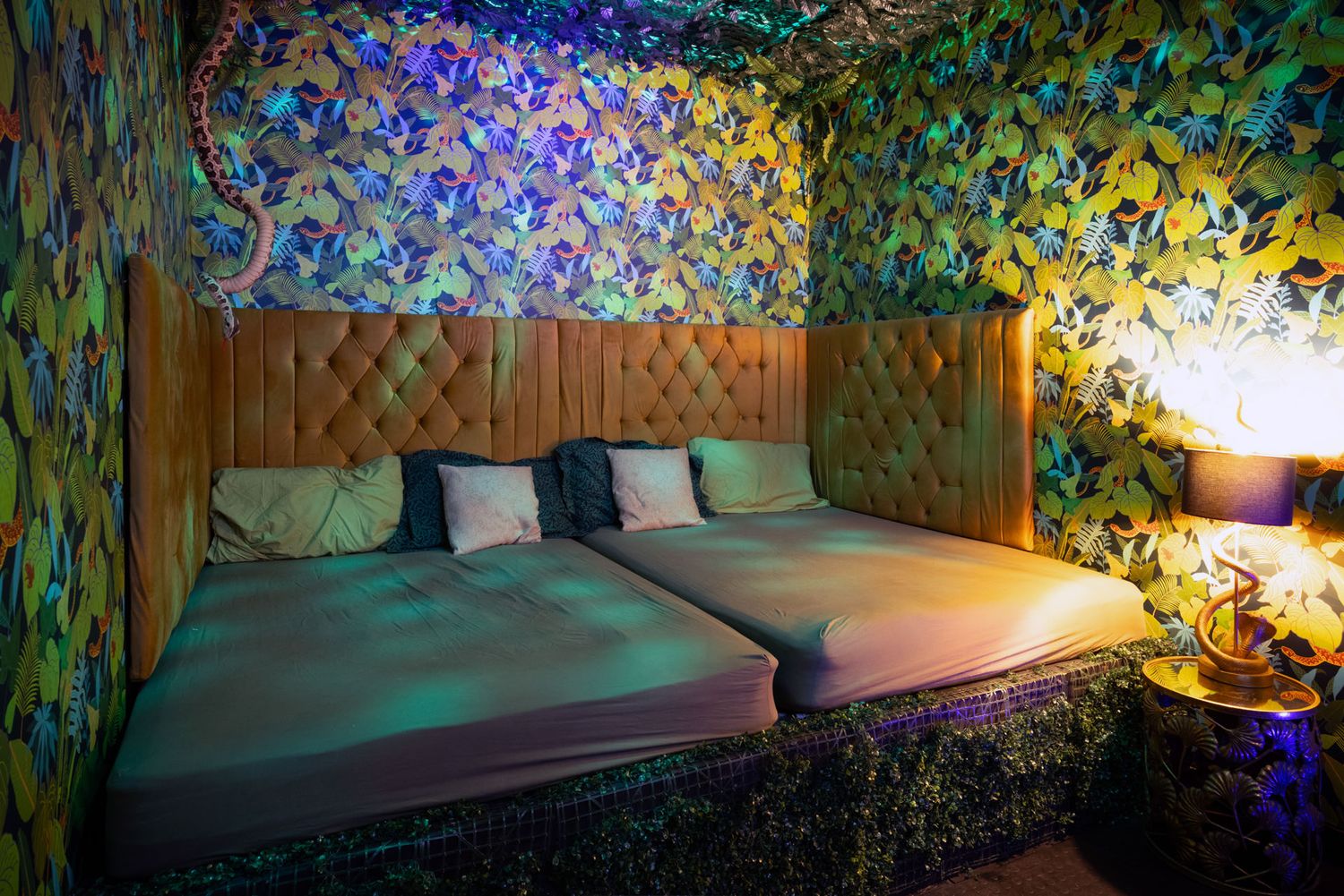 A cosy bed in a swingers club with colourful butterfly pattern walls and mood lighting creates a dreamy atmosphere.