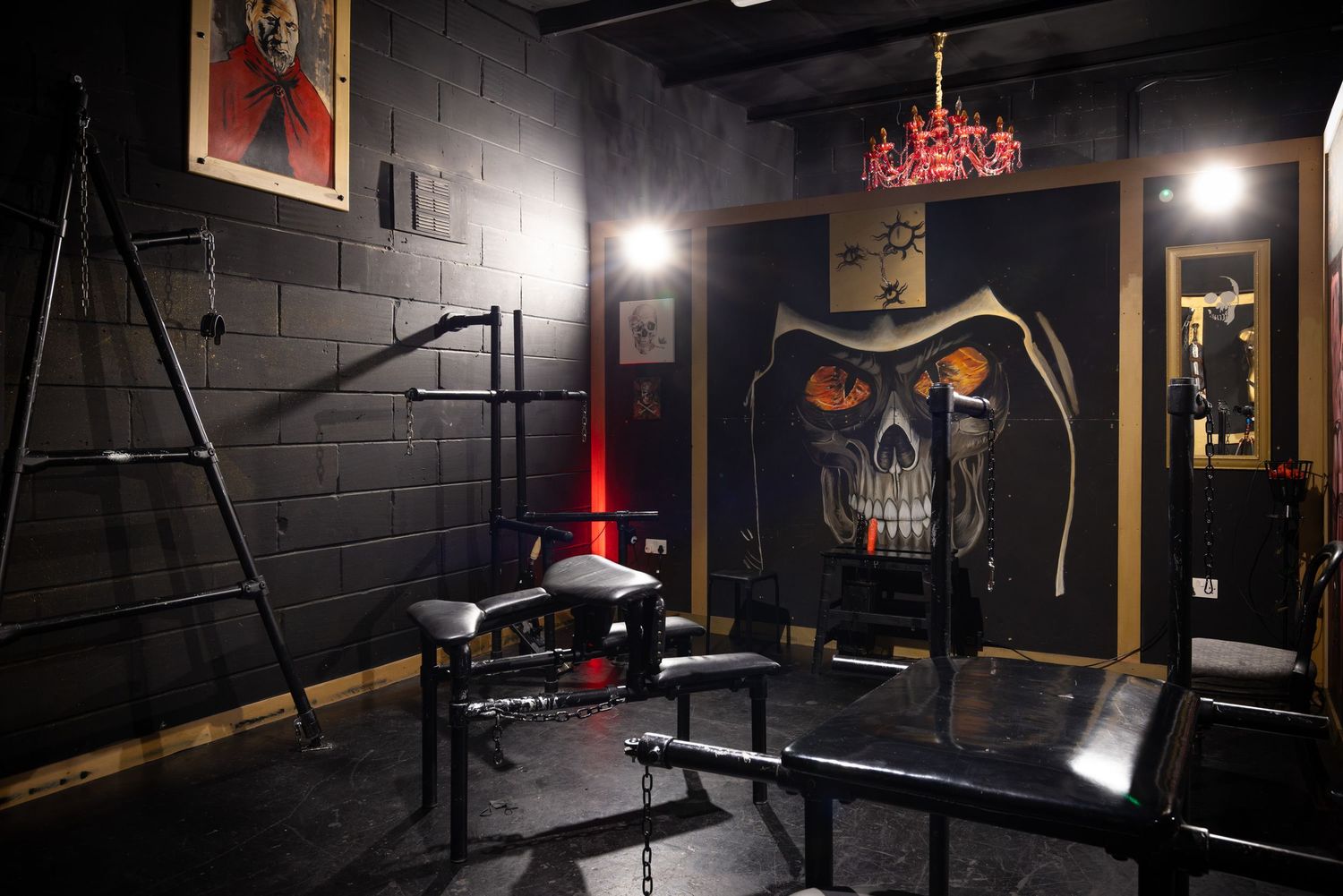 Dark dungeon-style room with black walls and illuminated artwork at Penthouse Playrooms Dunstable, creating a moody adult club interior