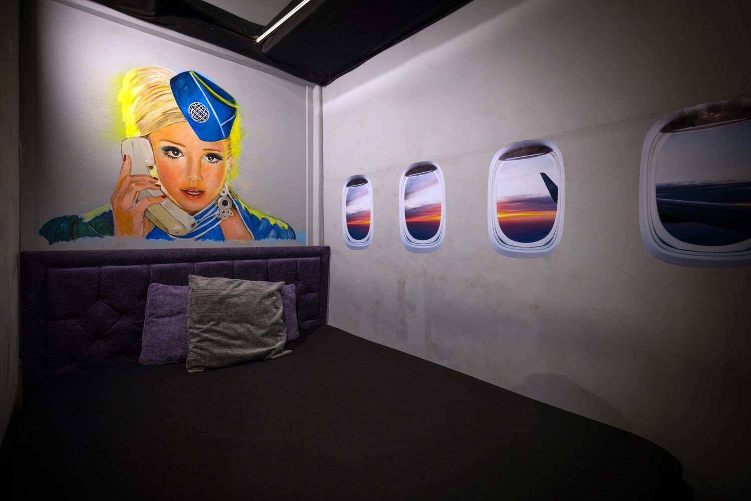 Gallery installation view showing colorful abstract artworks mounted on white walls with dramatic lighting. Shot in penthouse playrooms.