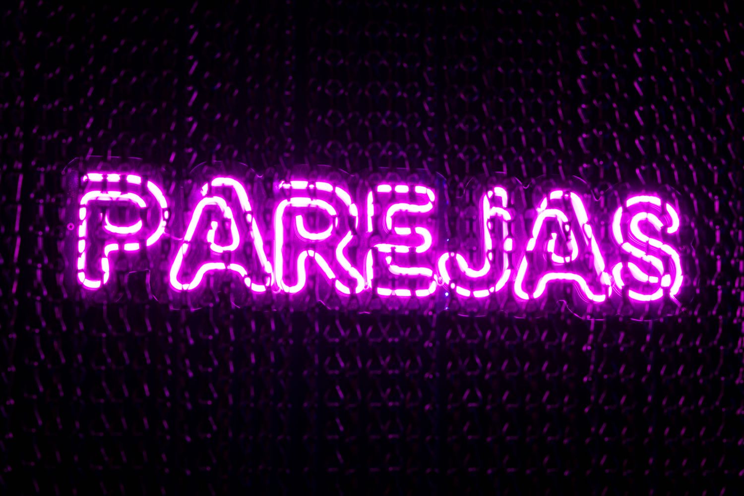 Purple neon lighting displays glowing text in bar signs creating a vibrant nightlife atmosphere.