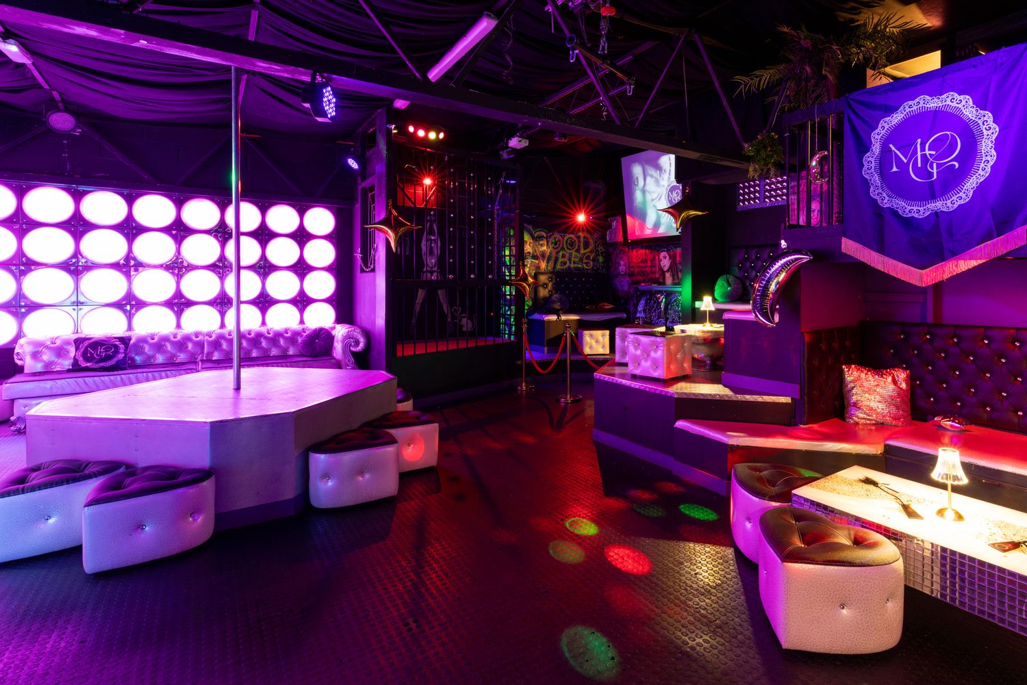 Vibrant purple nightclub interior with modern white seating and glowing LED lights creating an atmospheric party ambiance.