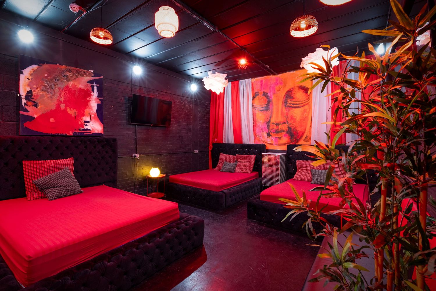 Red-lit lounge with plush seating at Penthouse Playrooms Dunstable, creating a moody adult club interior atmosphere