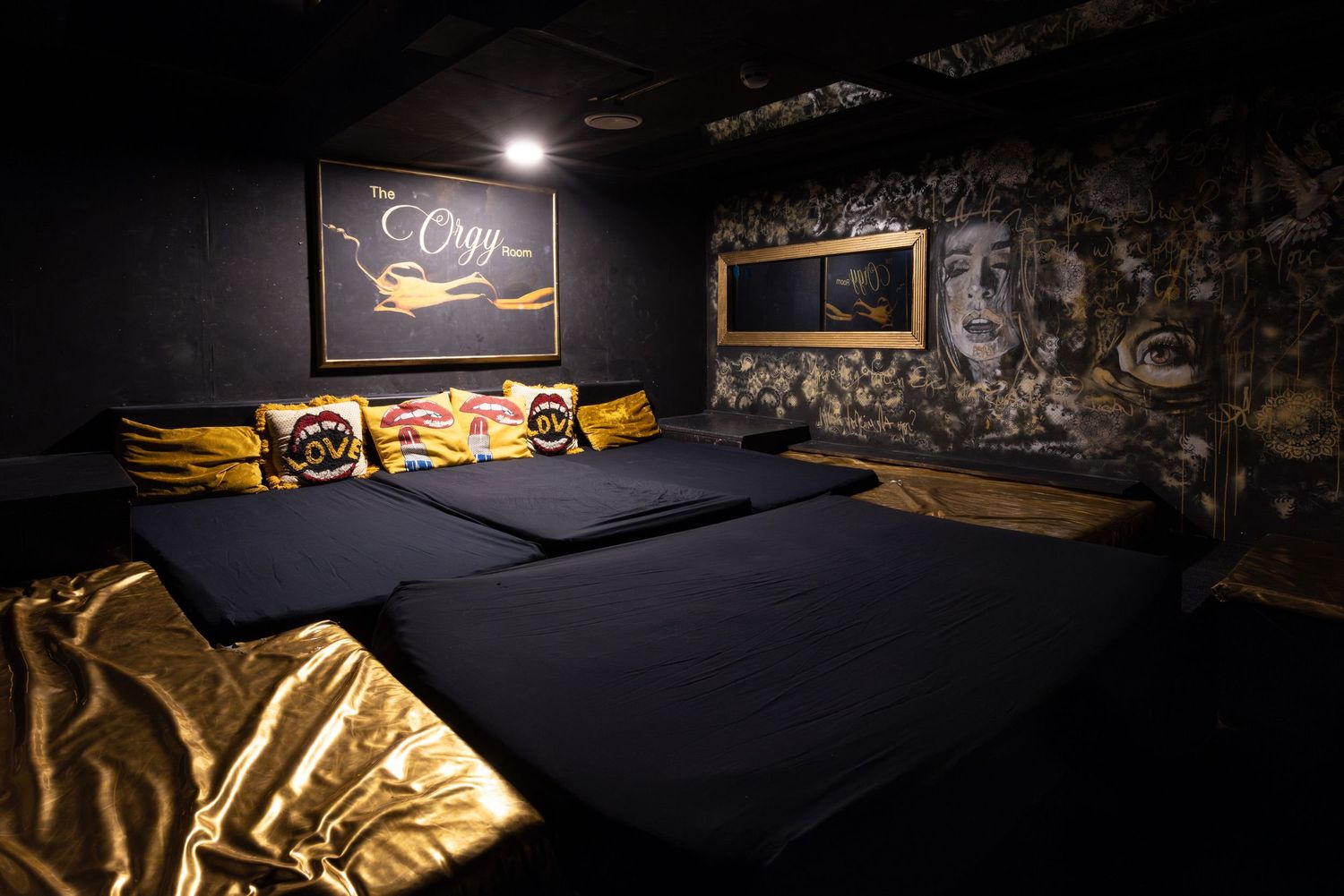 Dimly lit private room with gold-toned artwork on dark stone walls at Penthouse Playrooms Dunstable, creating a moody adult club interior