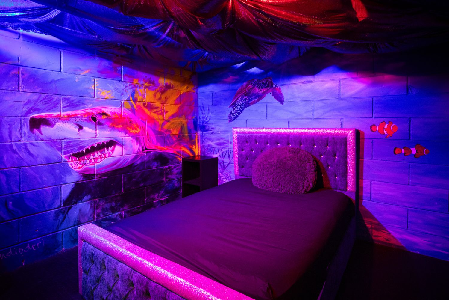 Blue dinosaur skeleton displays mounted on walls and platforms glow under dramatic purple and red lighting in a museum exhibit.