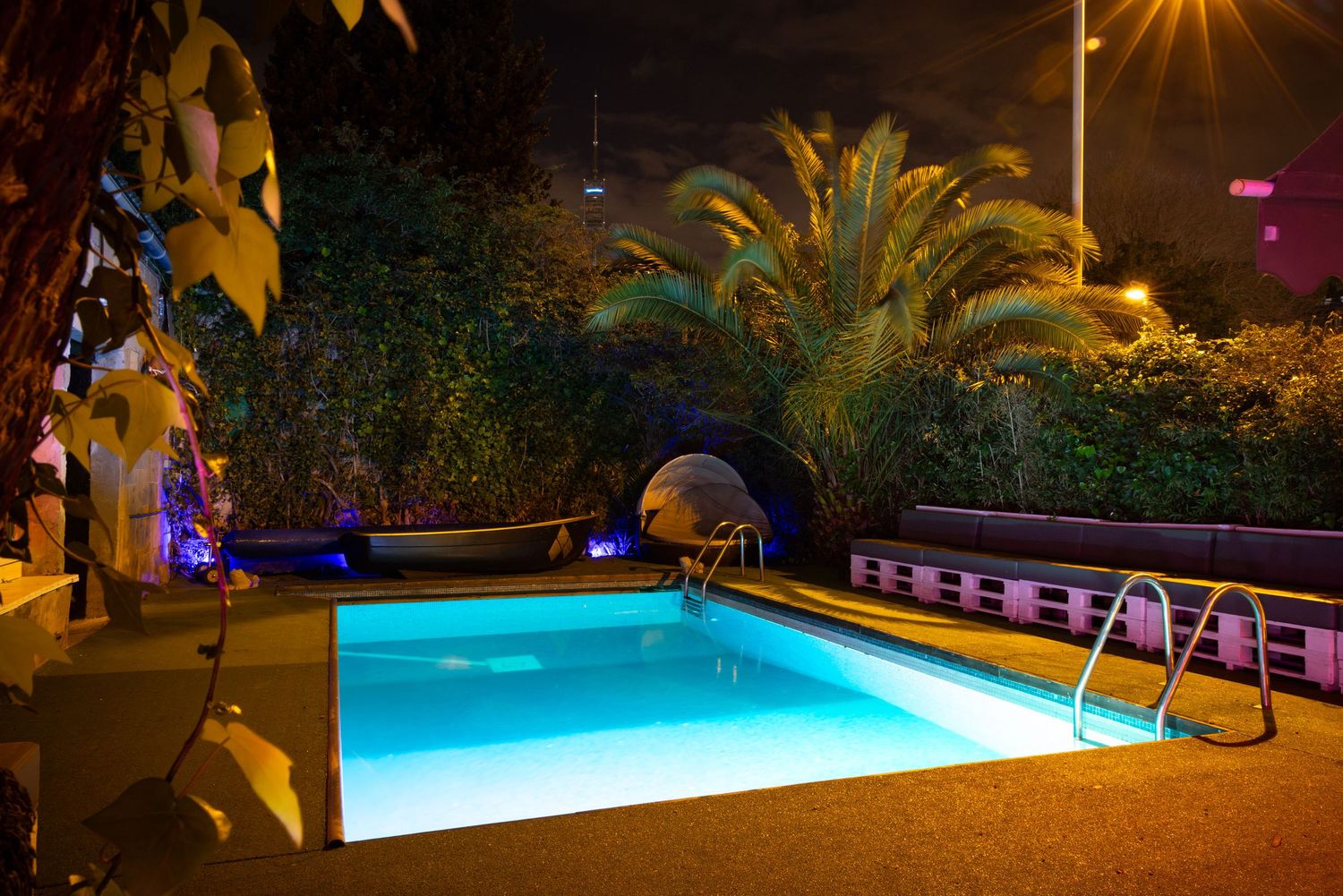 Outdoor pool with palm trees and ambient lighting at Club Oops Barcelona, creating a luxurious nighttime club atmosphere