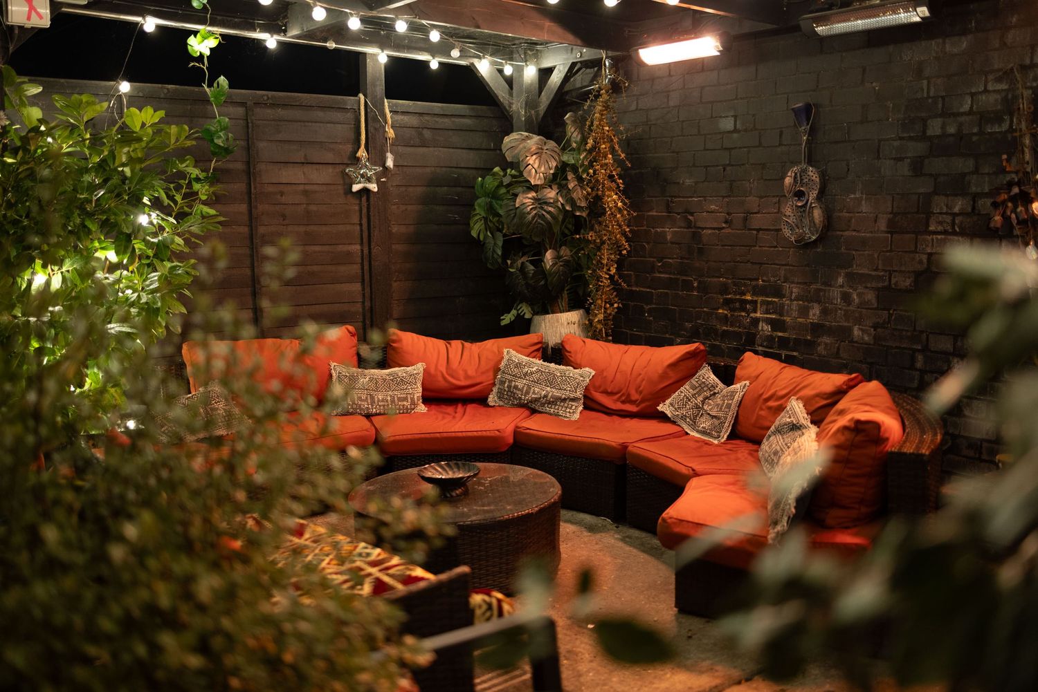 Outdoor patio with orange cushions and string lights at Penthouse Playrooms Dunstable, creating a warm nighttime club atmosphere