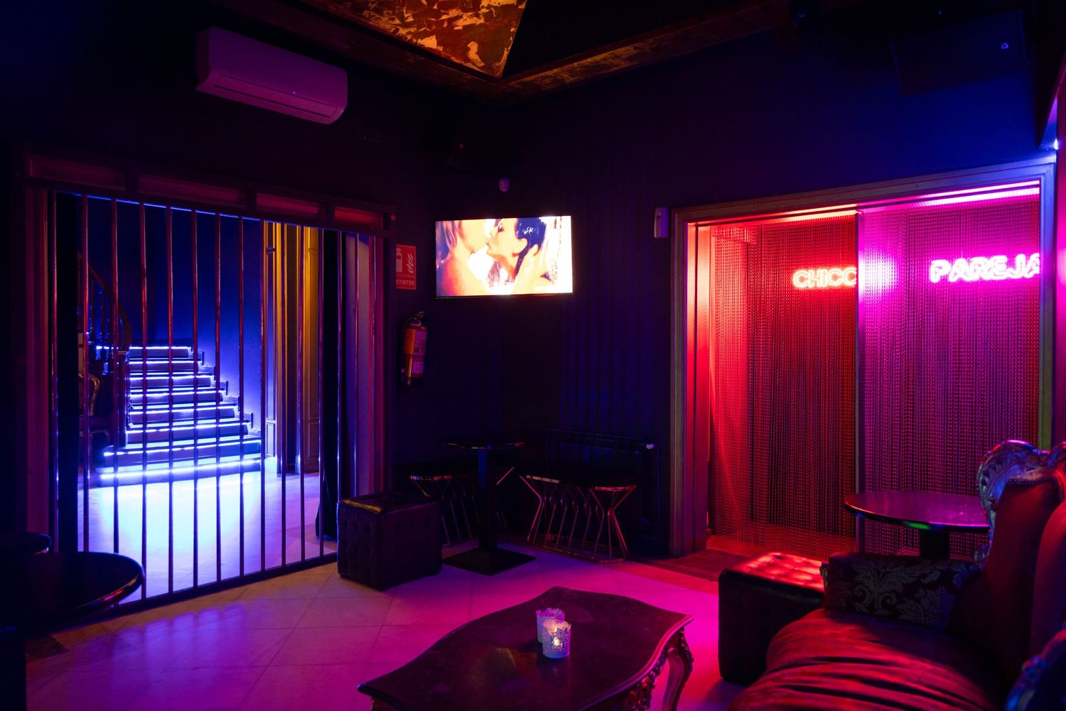 Dimly lit nightclub interior with pink and purple neon lighting at Club Oops Barcelona, creating a moody, atmospheric vibe