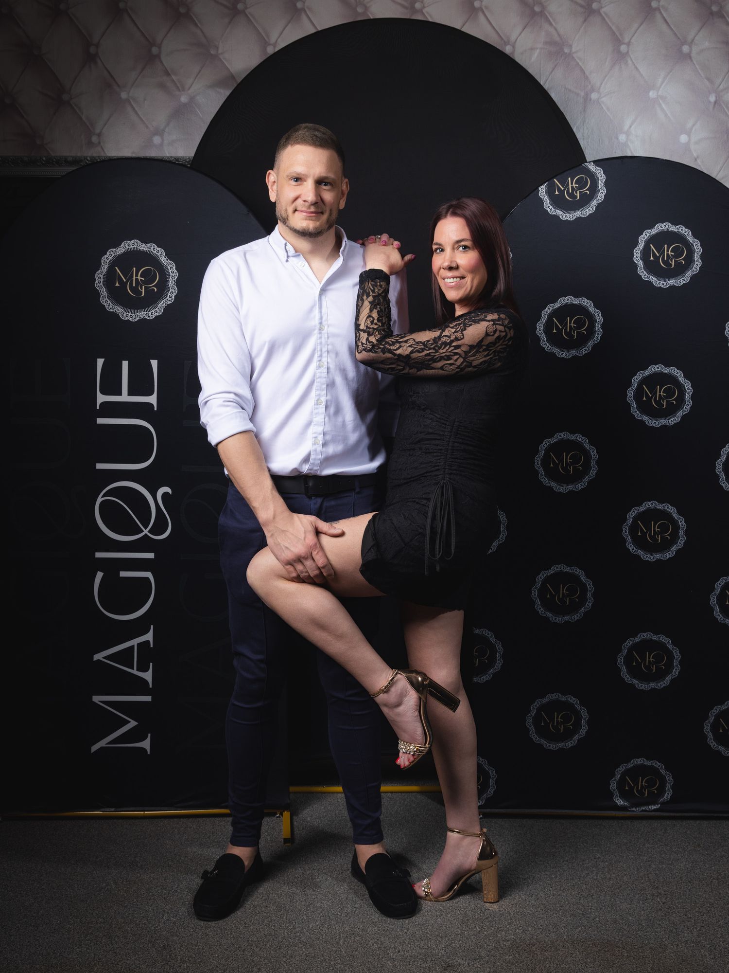 Event photography of a couple posing in front of a black backdrop.