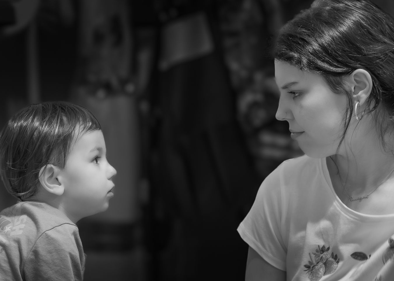 Black and white close-up of a young child and mother gazing at each other face to face.