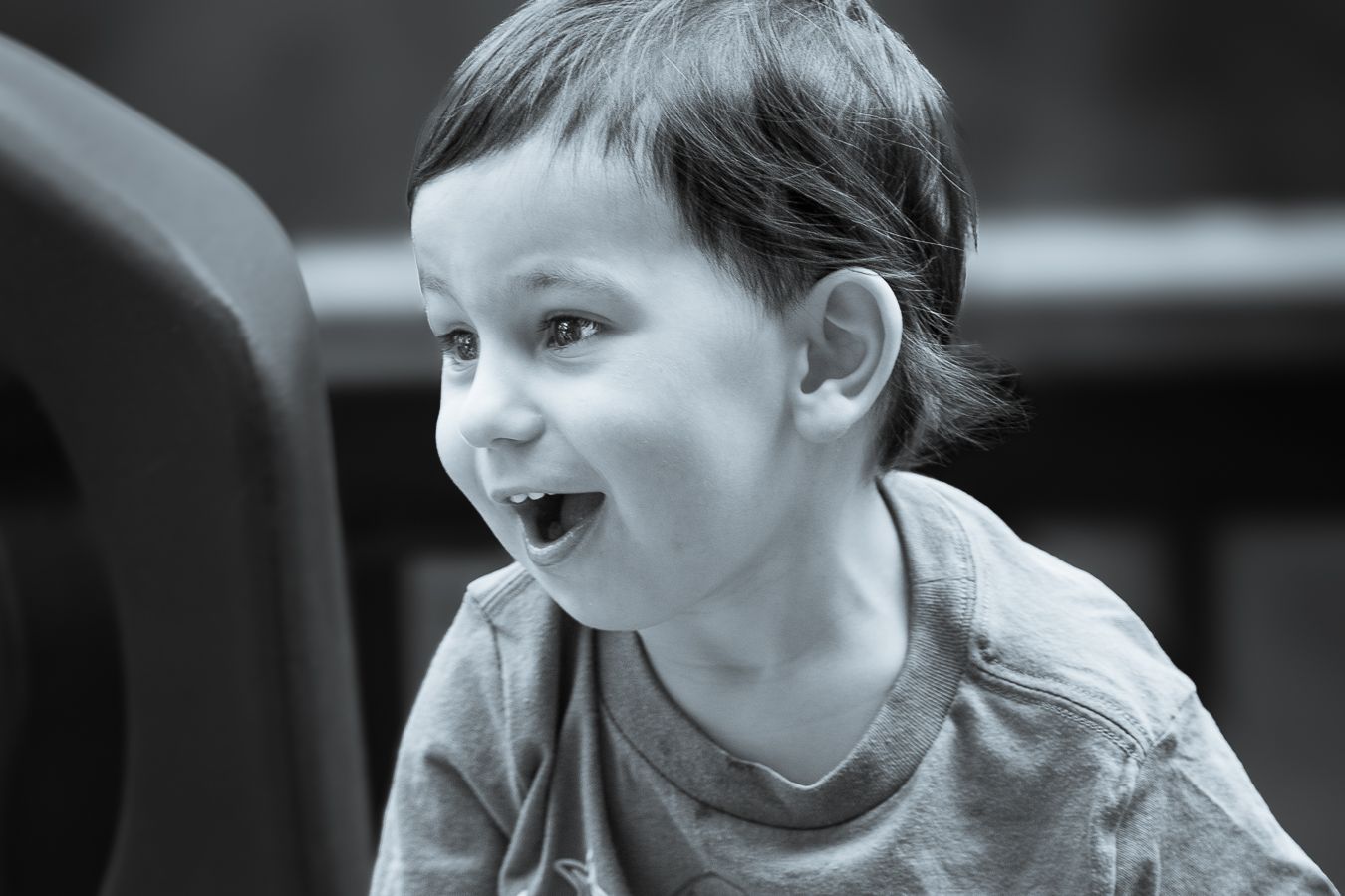 Happy toddler boy laughing with mouth open wide, close-up black and white portrait photo.