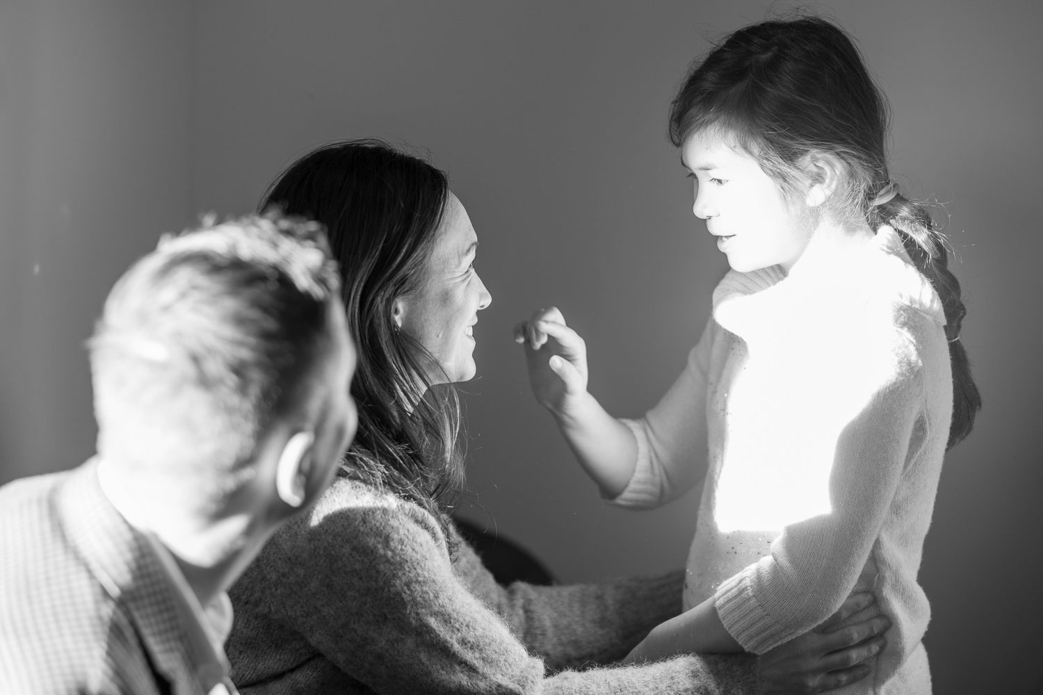 Black and white photo of woman applying makeup to young girl under bright studio lighting.