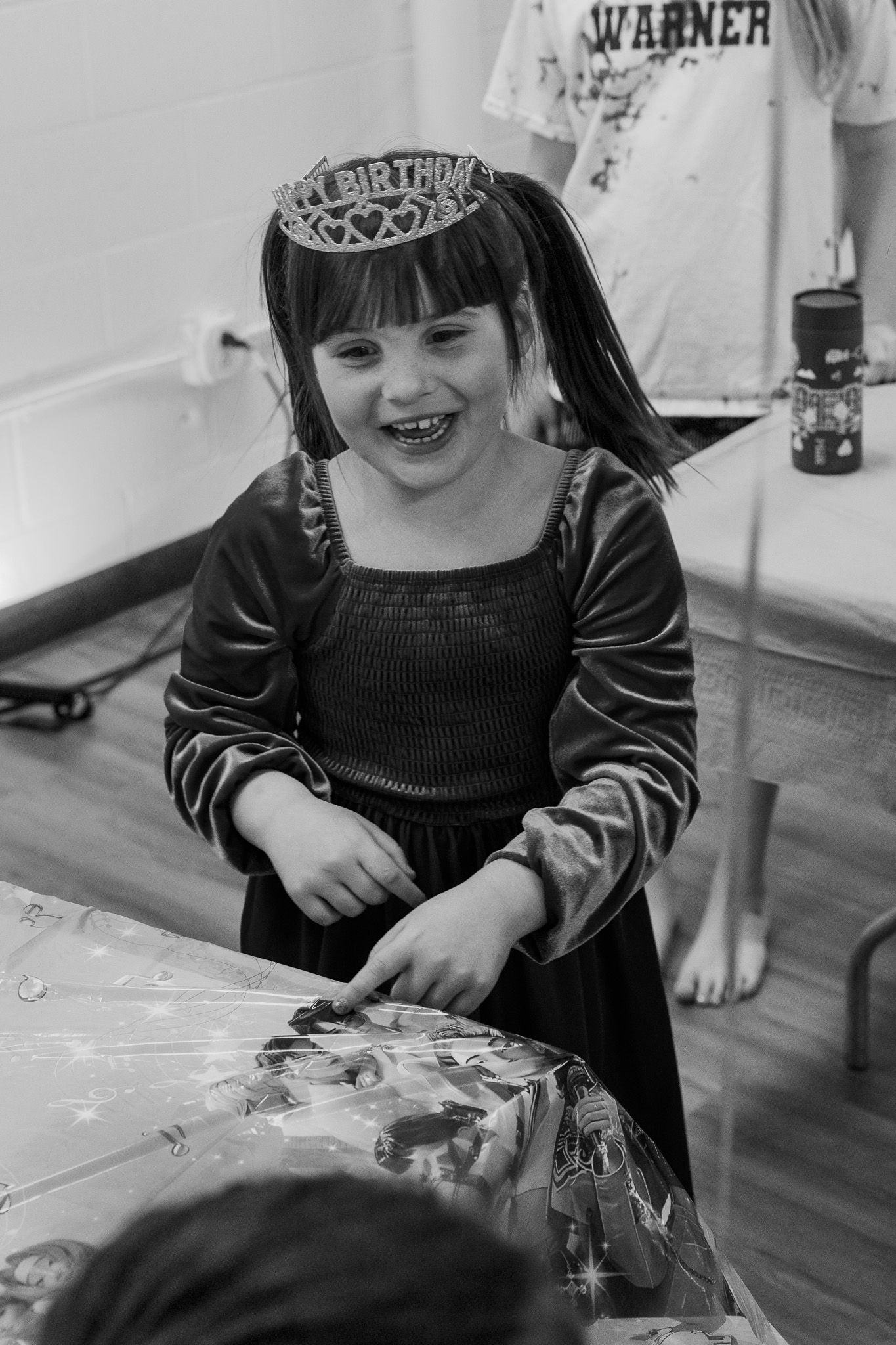 Happy young girl wearing a birthday tiara and costume dress laughing at her birthday party.