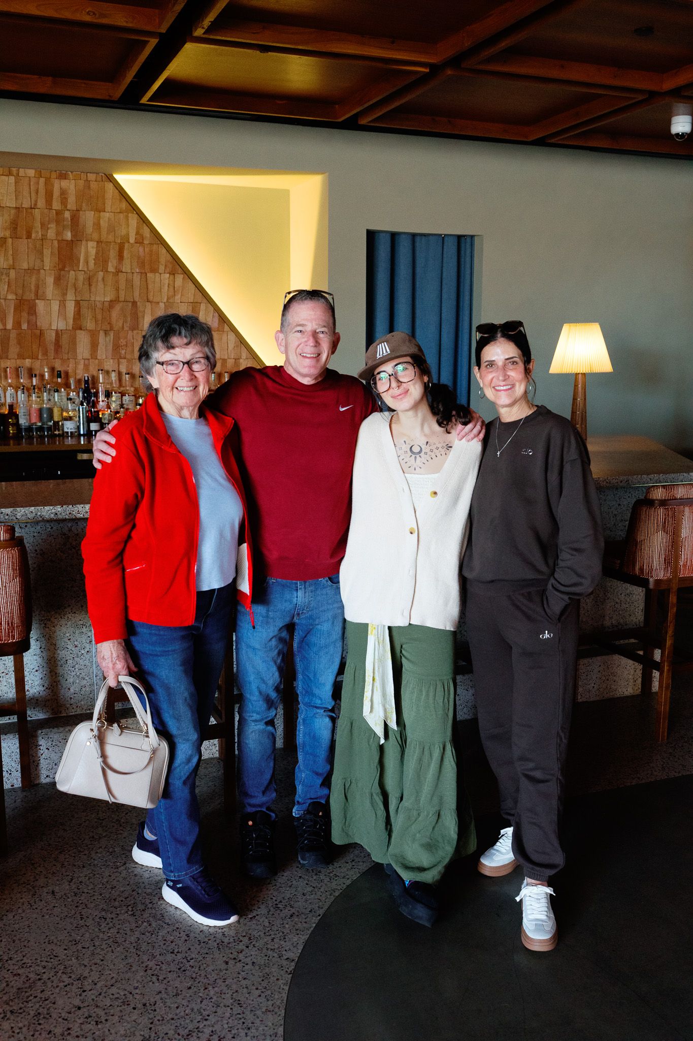 Two older adults and two younger women smiling together inside a modern restaurant bar setting.