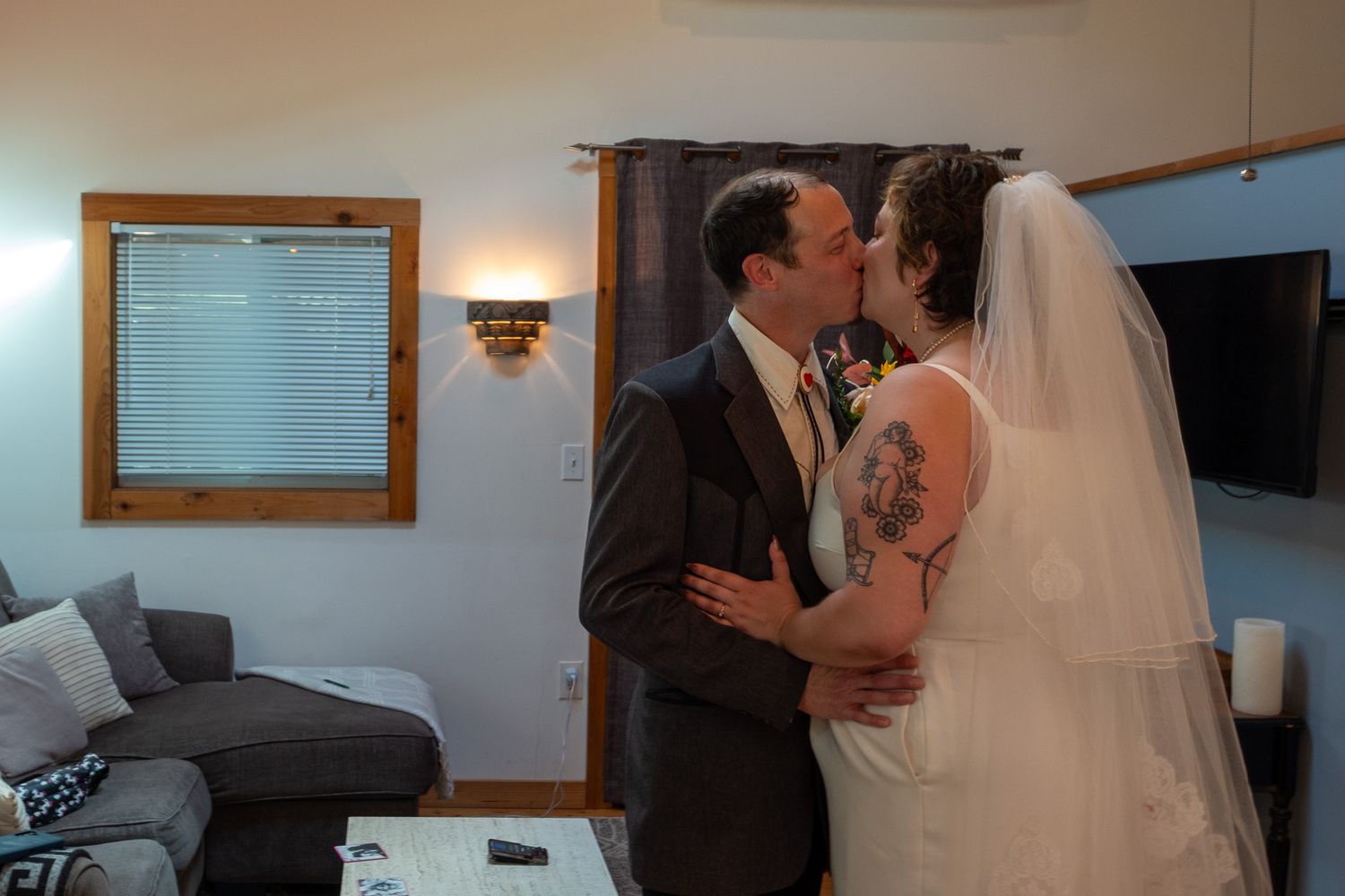 Newlywed couple shares a tender first kiss indoors after their wedding ceremony.