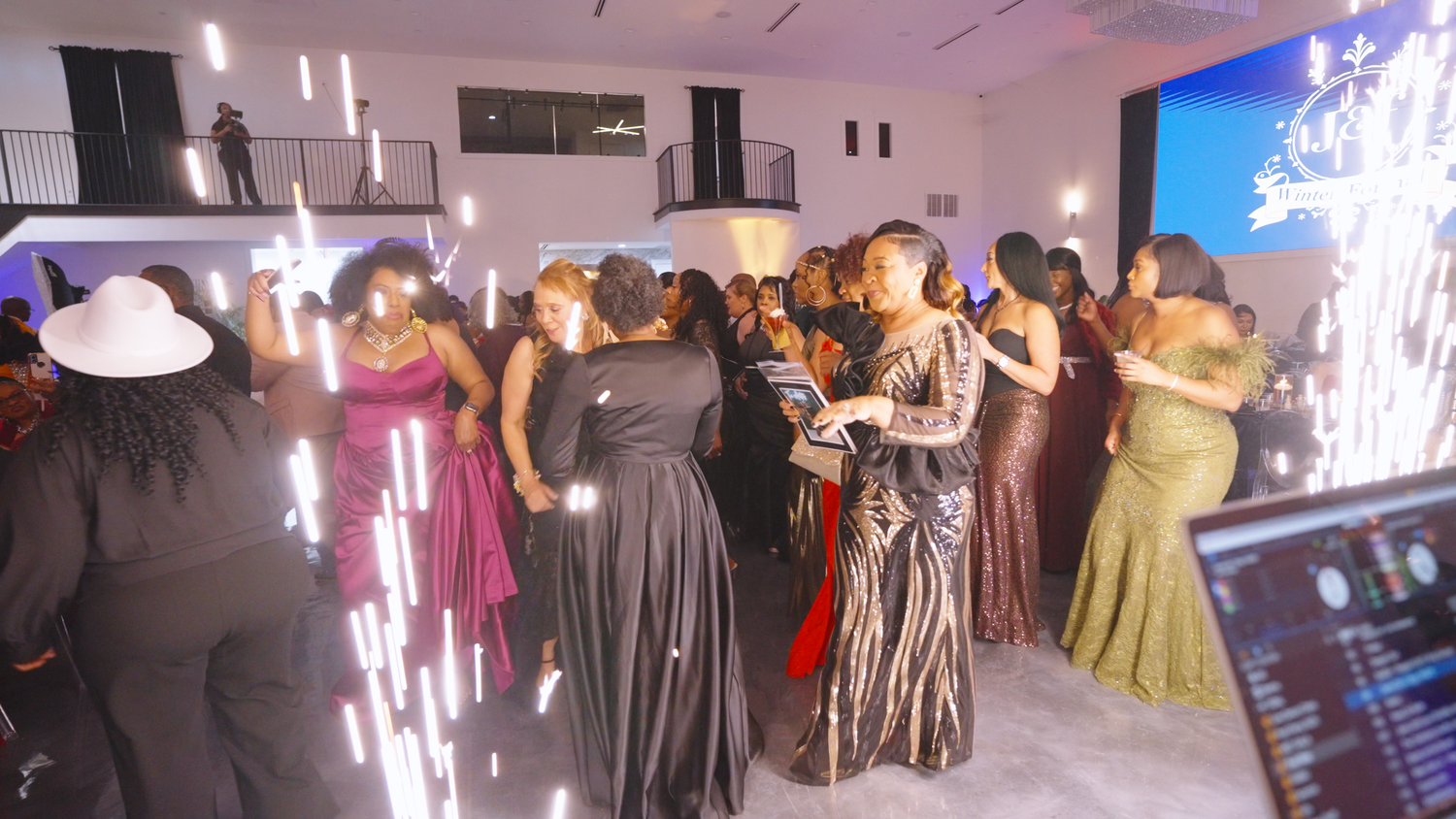 A group of people in formal evening gowns dancing at an elegant party with sparklers and lighting effects in the background by Kin & Lens