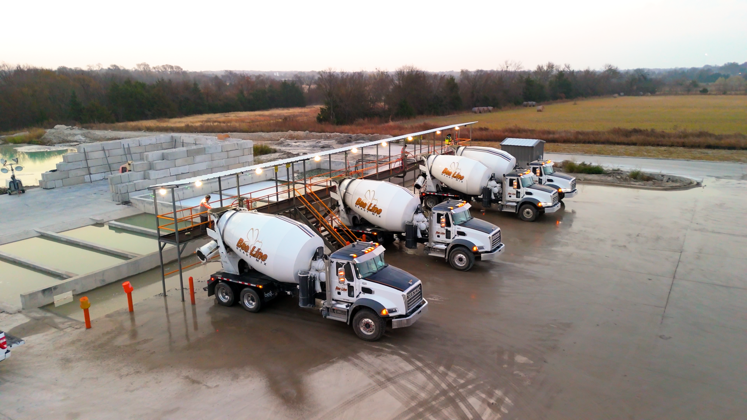 Concrete mixer trucks parked at batching plant yard captured by Kin & Lens Creative Media construction photographer in Dallas Fort Worth