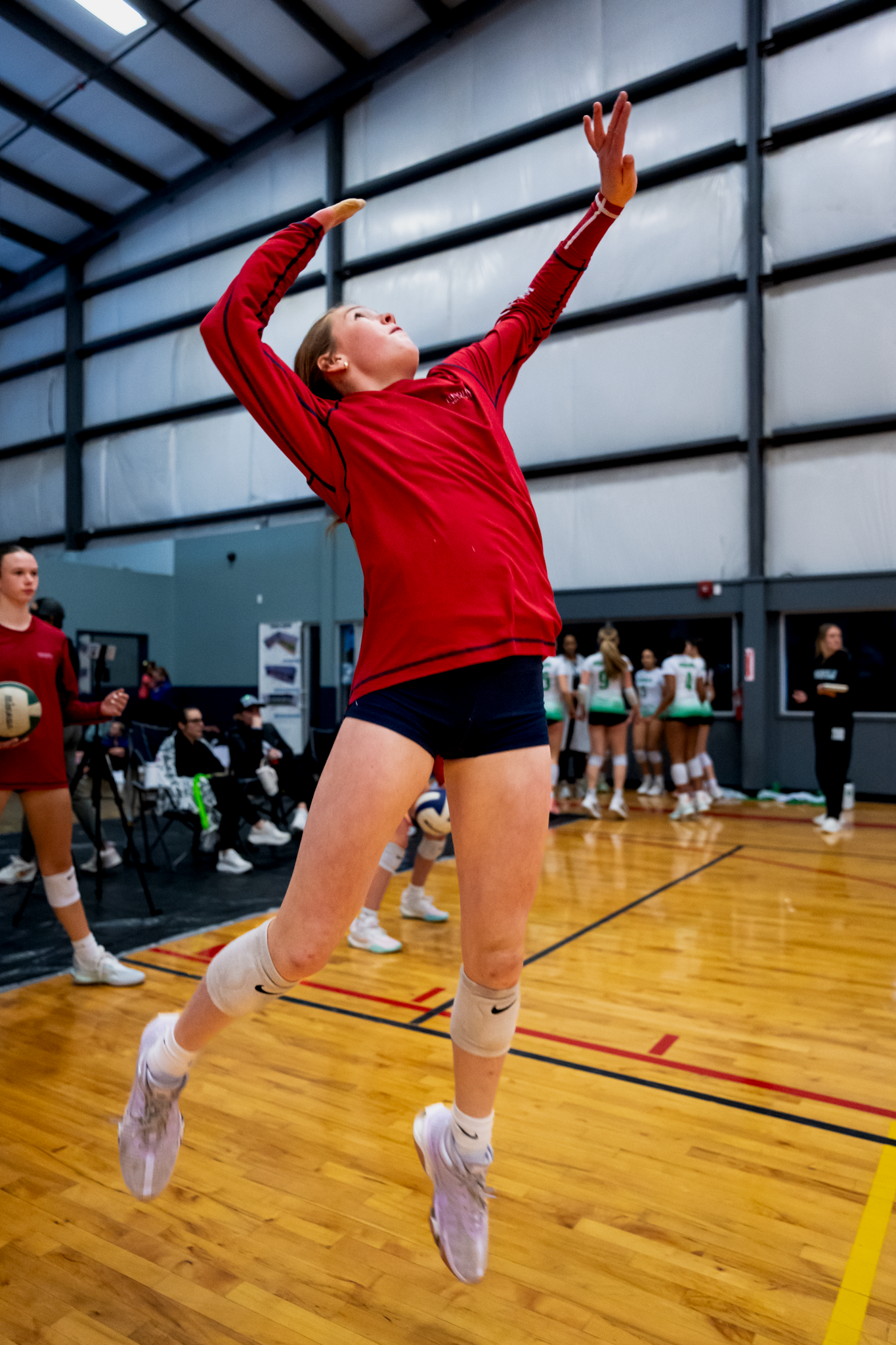 Volleyball player in red uniform performing diving save sequence on wooden court in Dallas, TX by Kin & Lens Creative Media