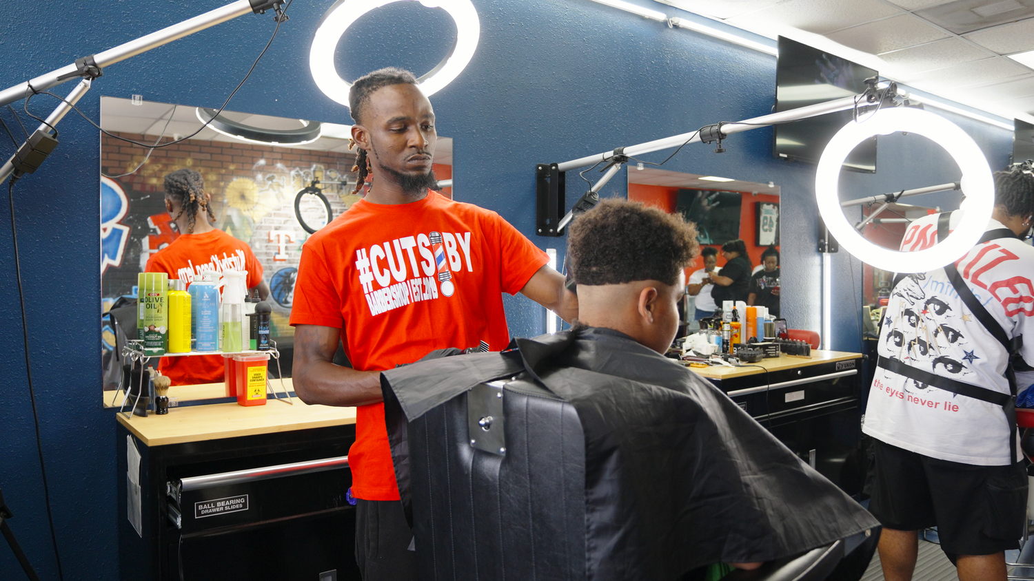 Barber cutting hair inside local barbershop captured by Kin & Lens Creative Media lifestyle photographer in Dallas Fort Worth