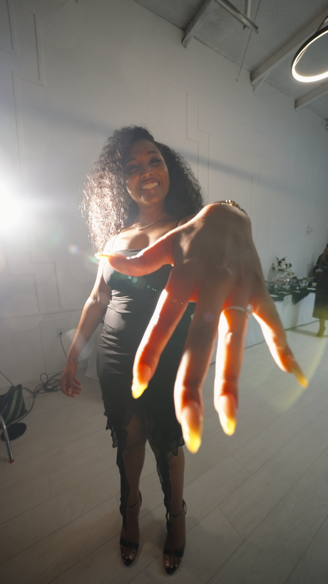 Woman brightly back lit with a hand extended forward showing off engagement ring shot by Kin & Lens Creative Media.