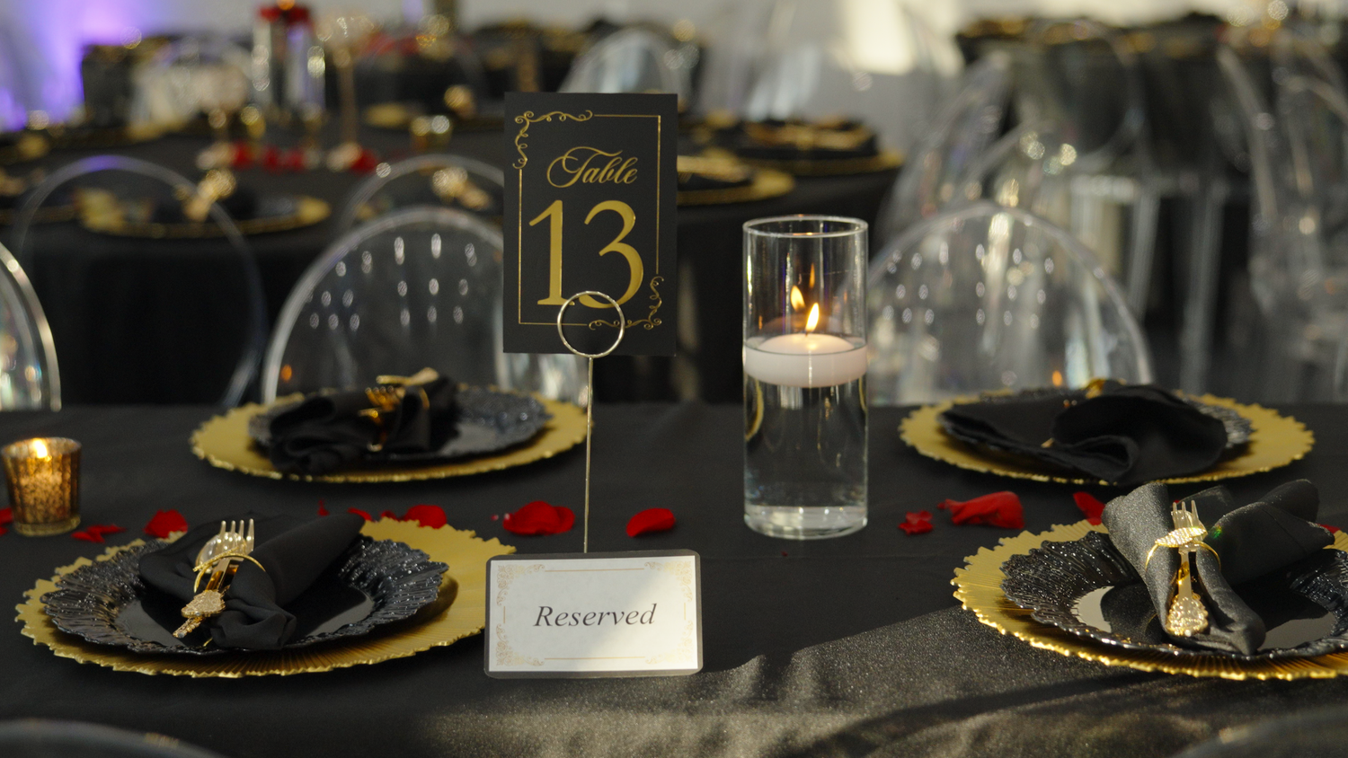 Elegant table settings with gold-rimmed charger plates and black accents create a luxurious dining atmosphere shot by Kin & Lens Creative