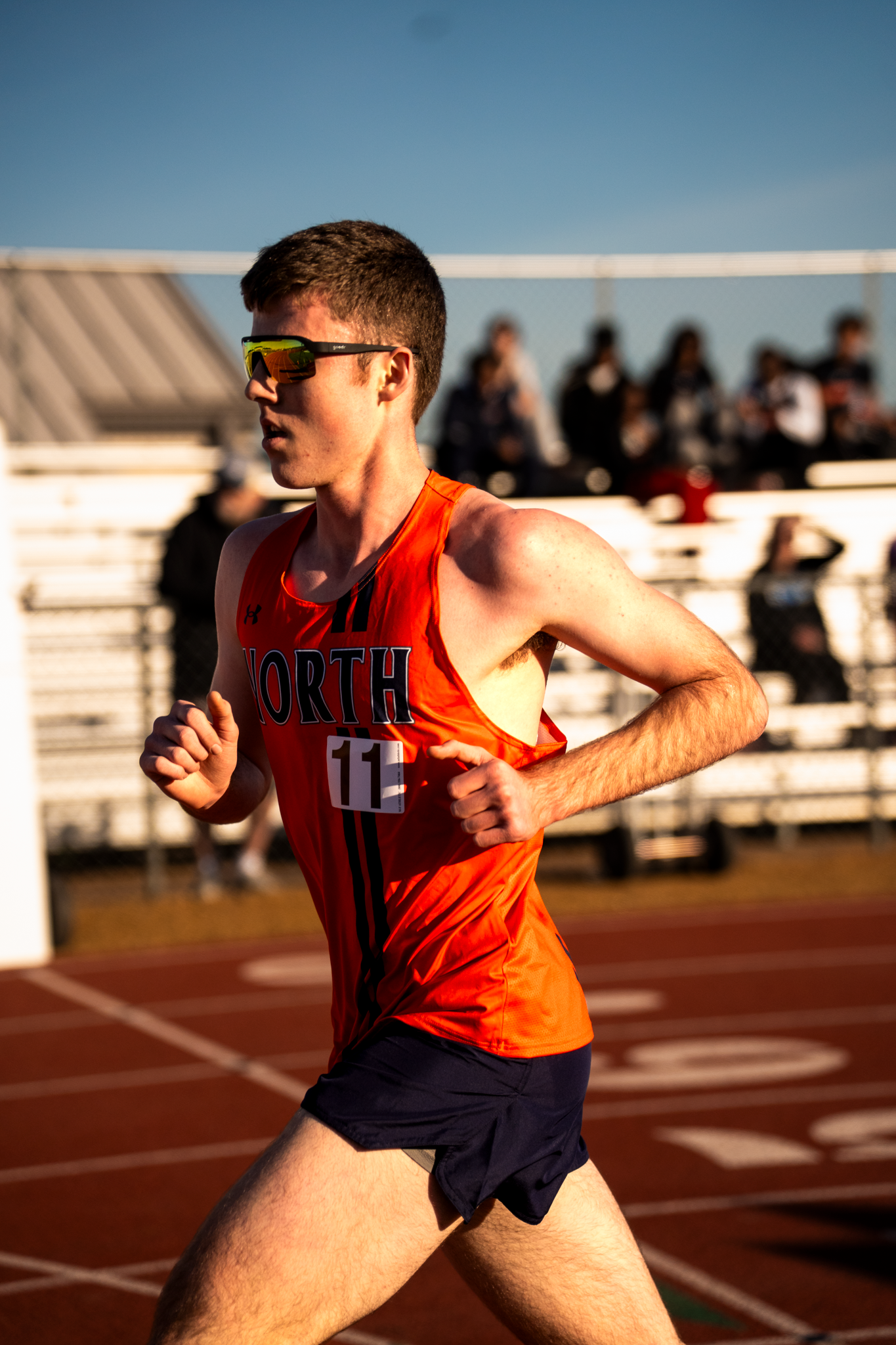Track athletes sprinting during competitive race on outdoor track.