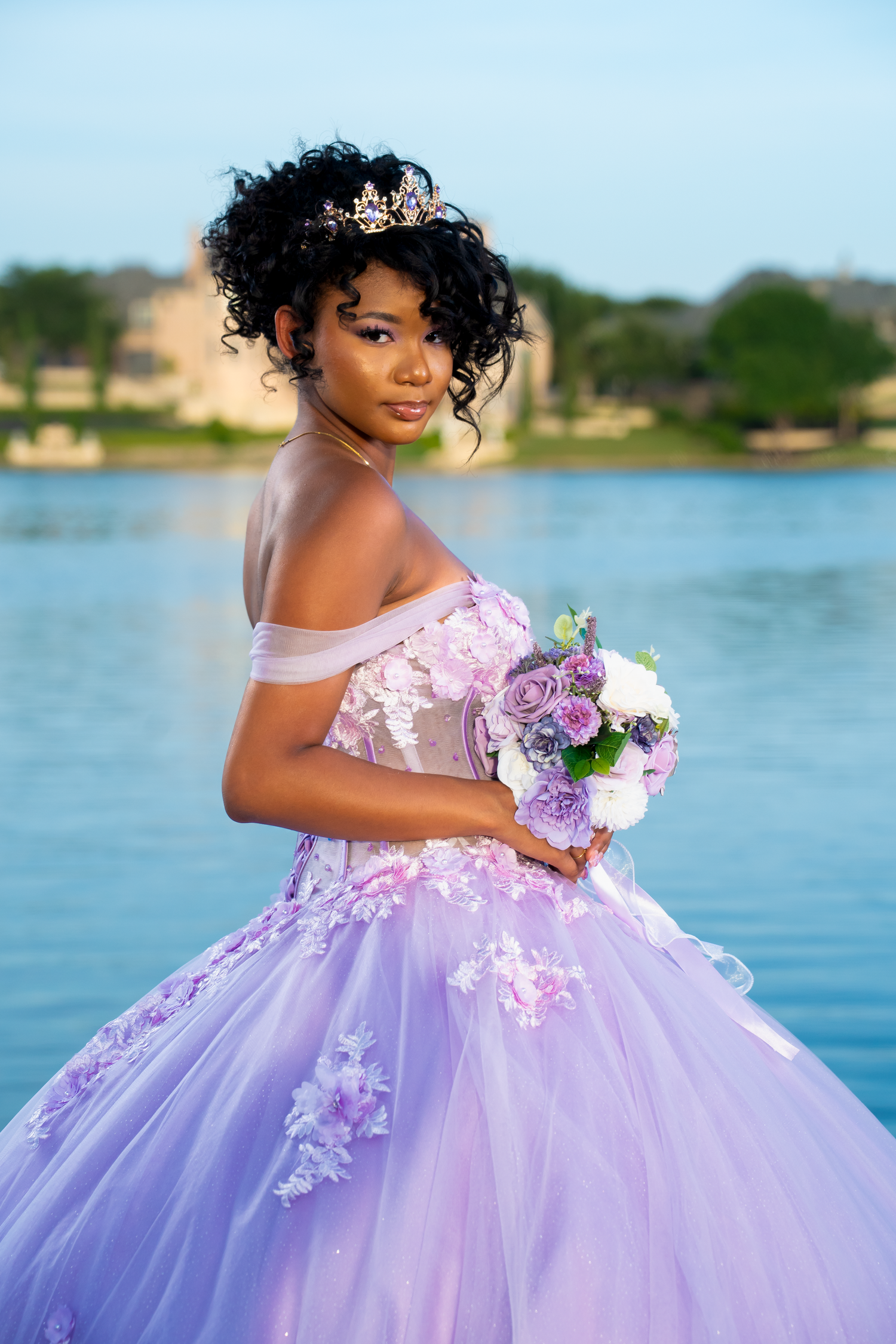 A flowing purple princess gown with floral appliques photographed by a lake.