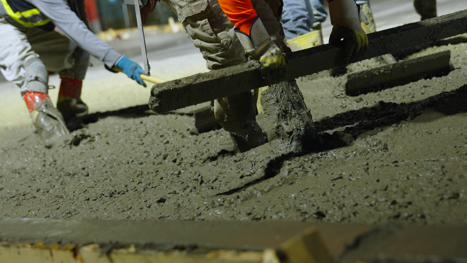 Concrete crew leveling freshly poured slab captured by Kin & Lens Creative Media construction photographer in Dallas Fort Worth