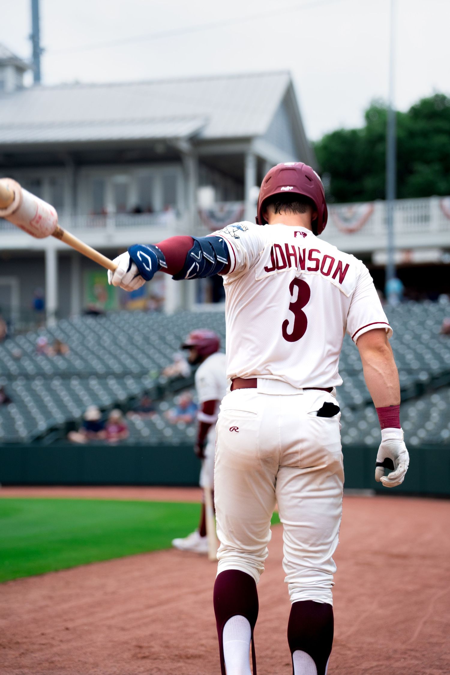 High school baseball player walking onto field with bat during game photographed by Kin & Lens Creative Media sports photographer in DFW