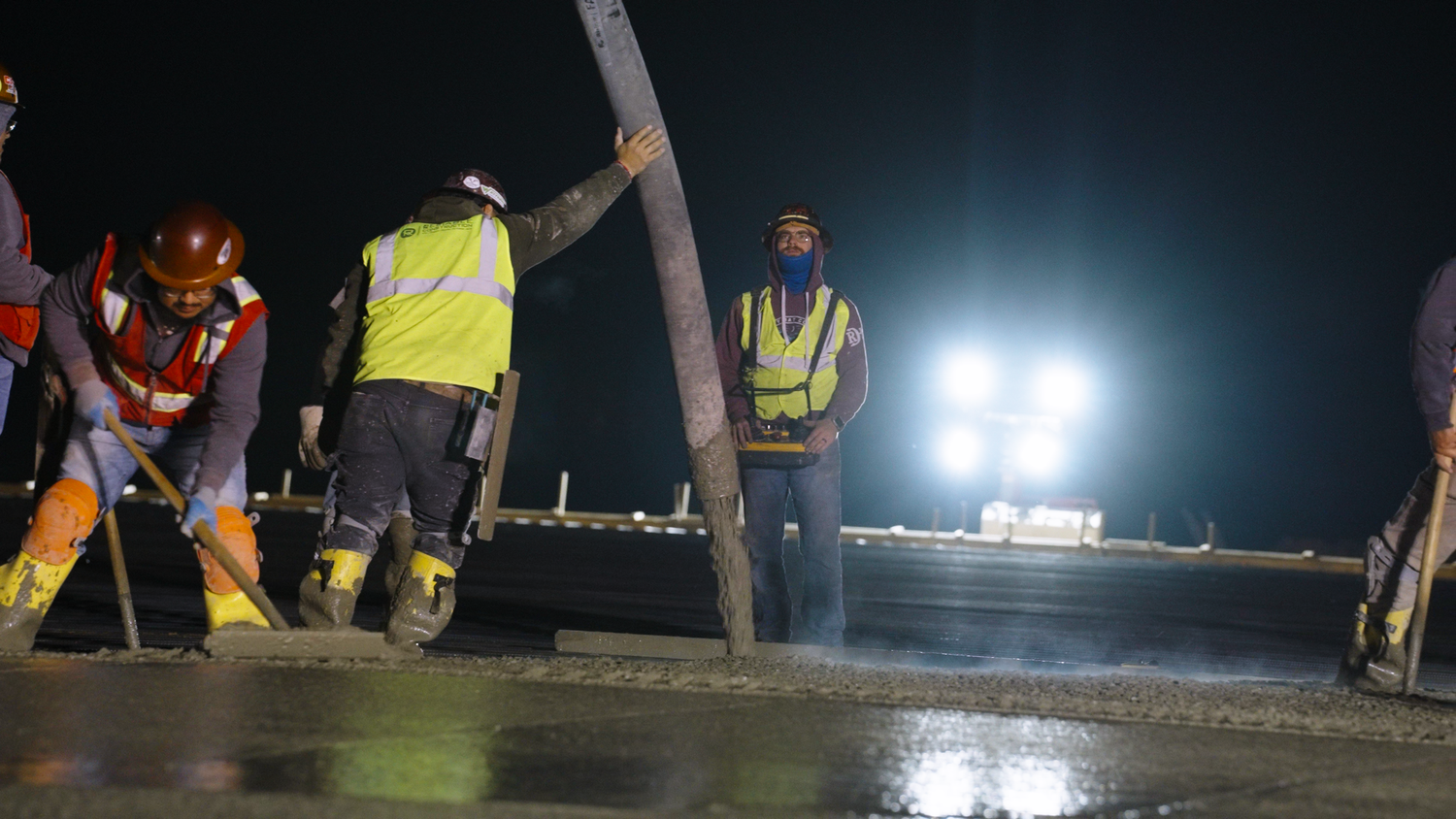 Construction crew leveling fresh concrete slab captured by Kin & Lens Creative Media construction photographer in Dallas Fort Worth