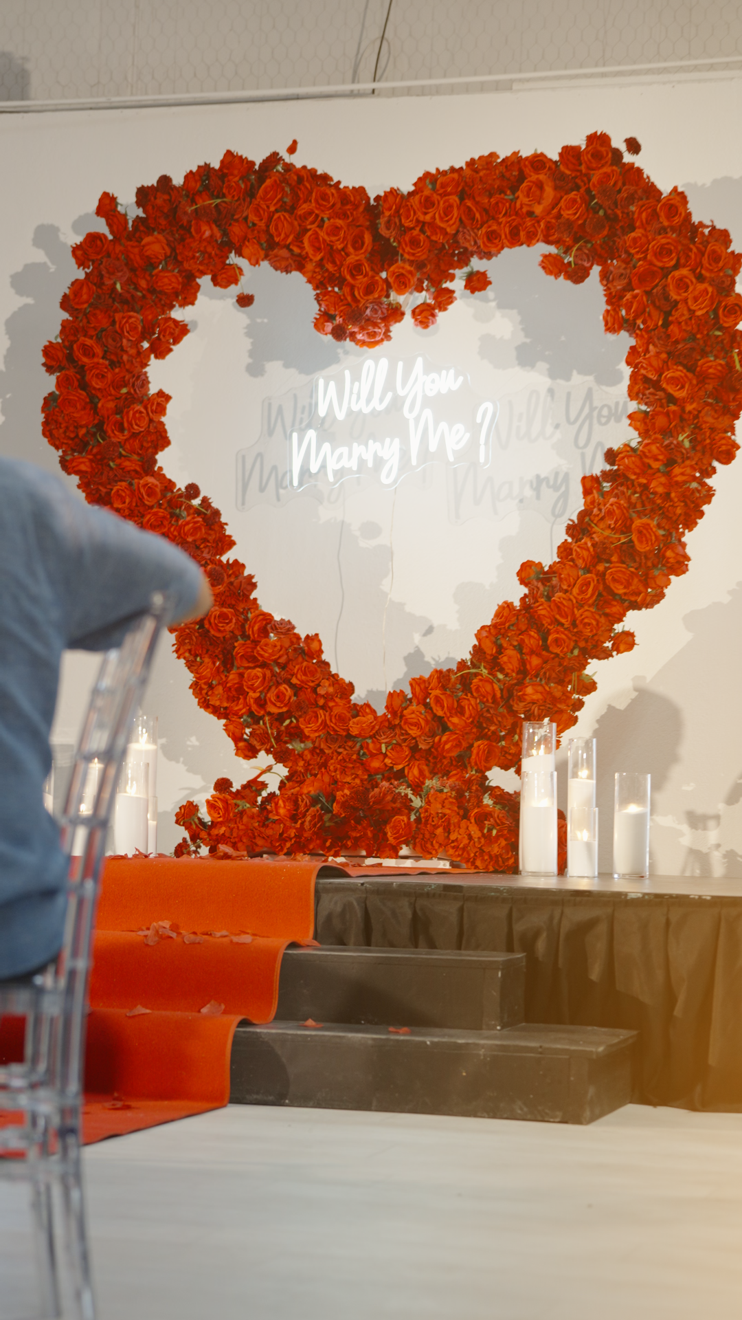 Large heart shaped red roses with illuminated 'Will You Marry Me?' text display for romantic proposal setup shot by Kin & Lens Creative