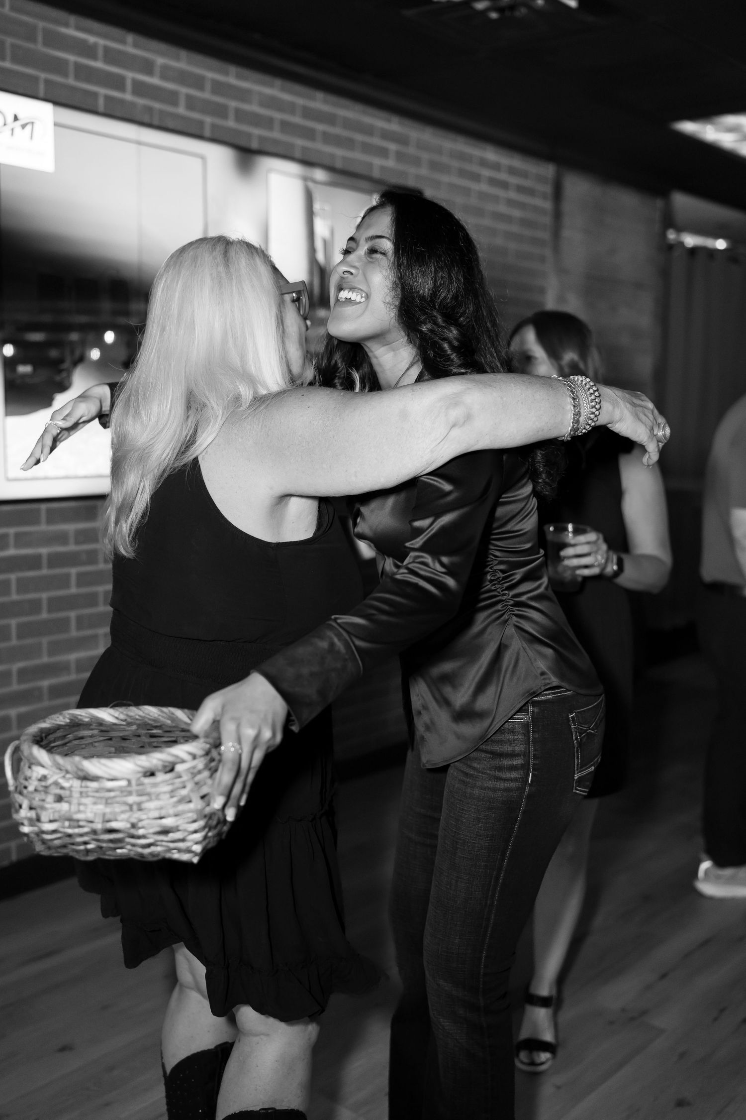 Black and white photo of two women embracing moment captured by Kin & Lens Creative Media event photographer in Dallas Fort Worth