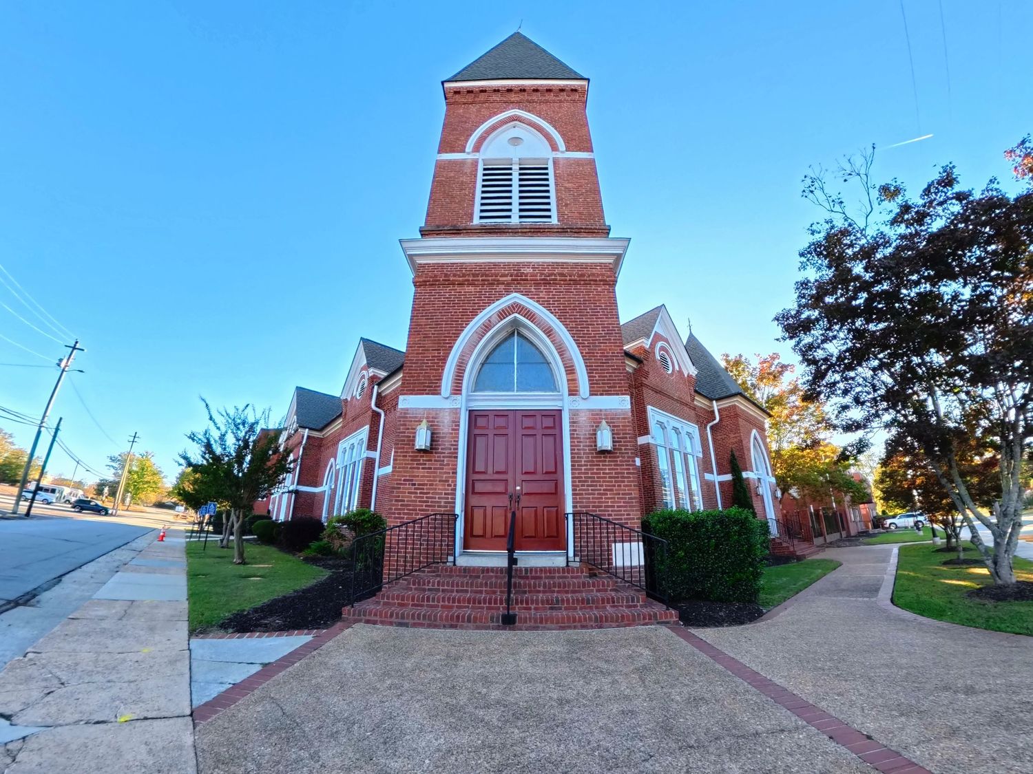 A red brick church building with white trim and arched windows photographed from multiple angles in panoramic view.