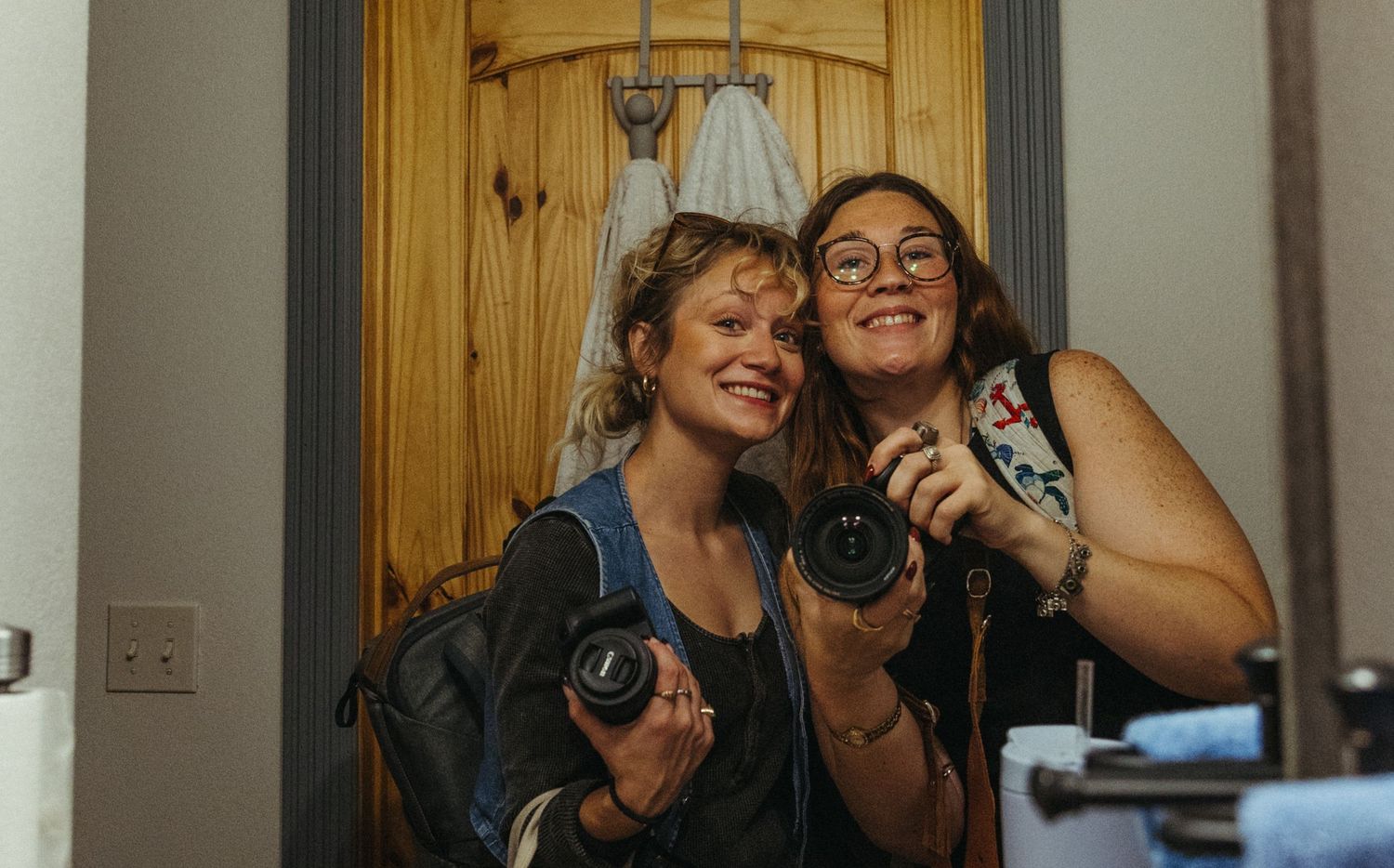 A group of photographers with cameras gather together in a rustic wood-paneled room.