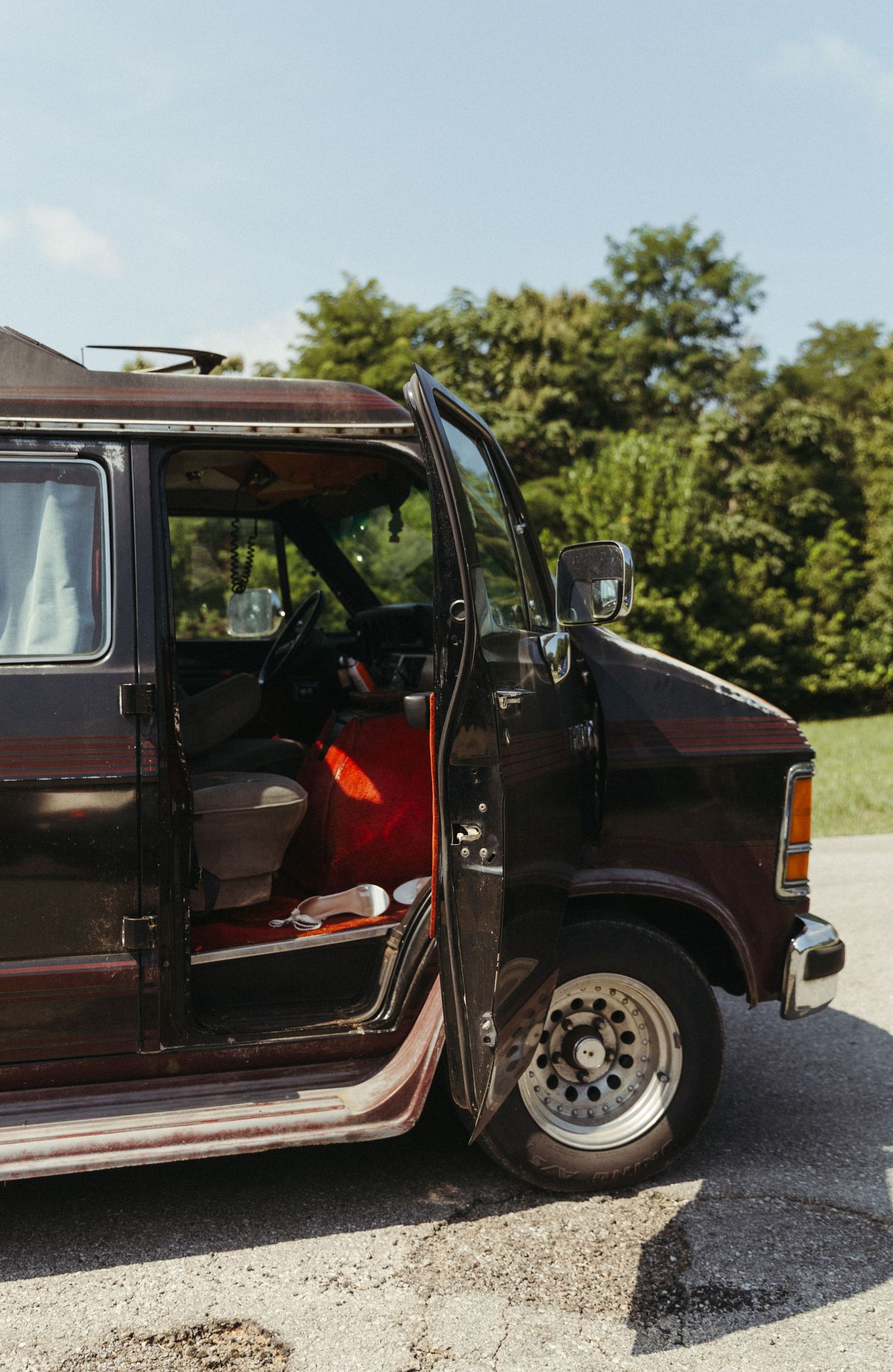 A series of shots showing the open doors of a vintage brown vehicle parked on a gravel road with trees in background.