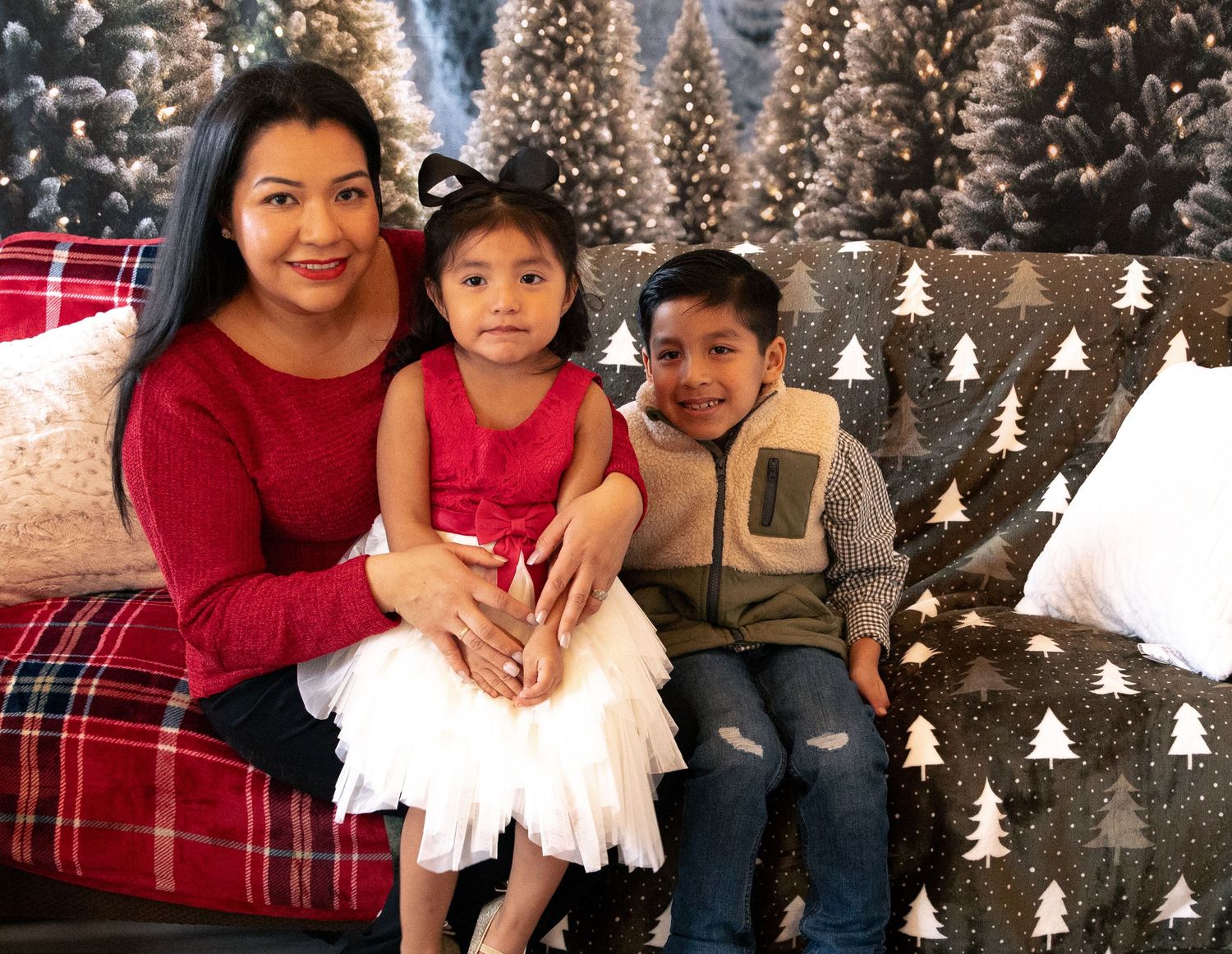Family portrait with holiday decorations and plaid backdrop.