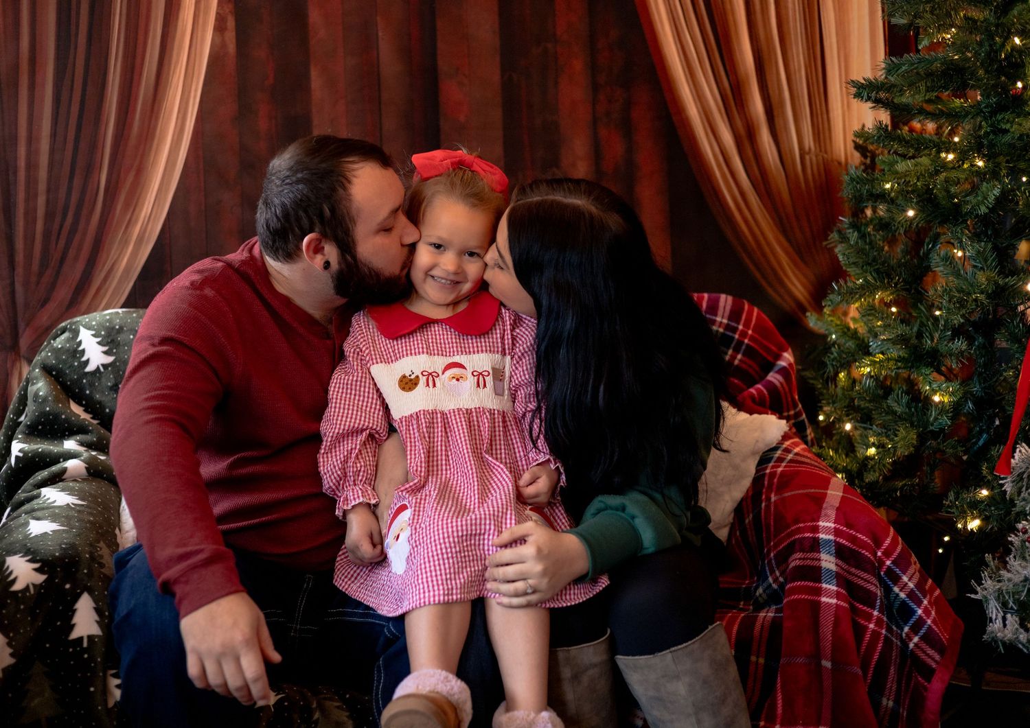 A series of four photos showing a baby in pink clothing being held and kissed near a Christmas tree.