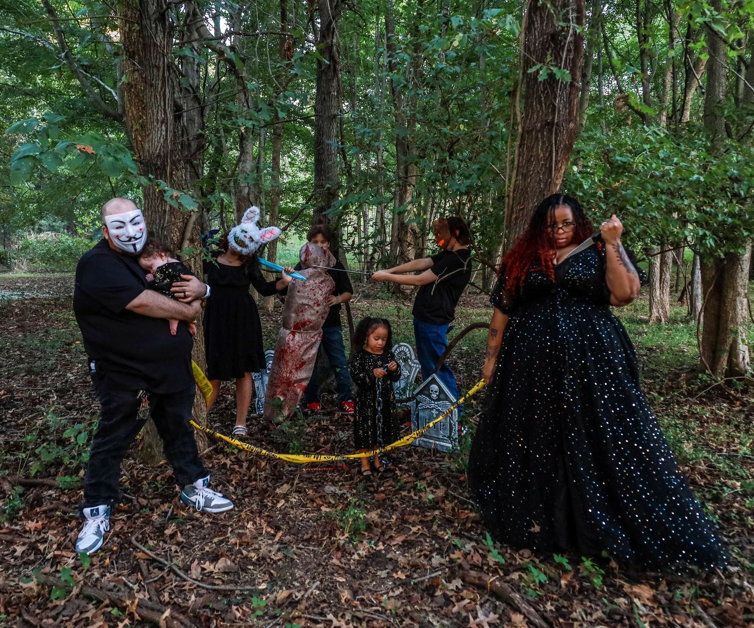 People walking through a dark forest path during a Halloween event.
