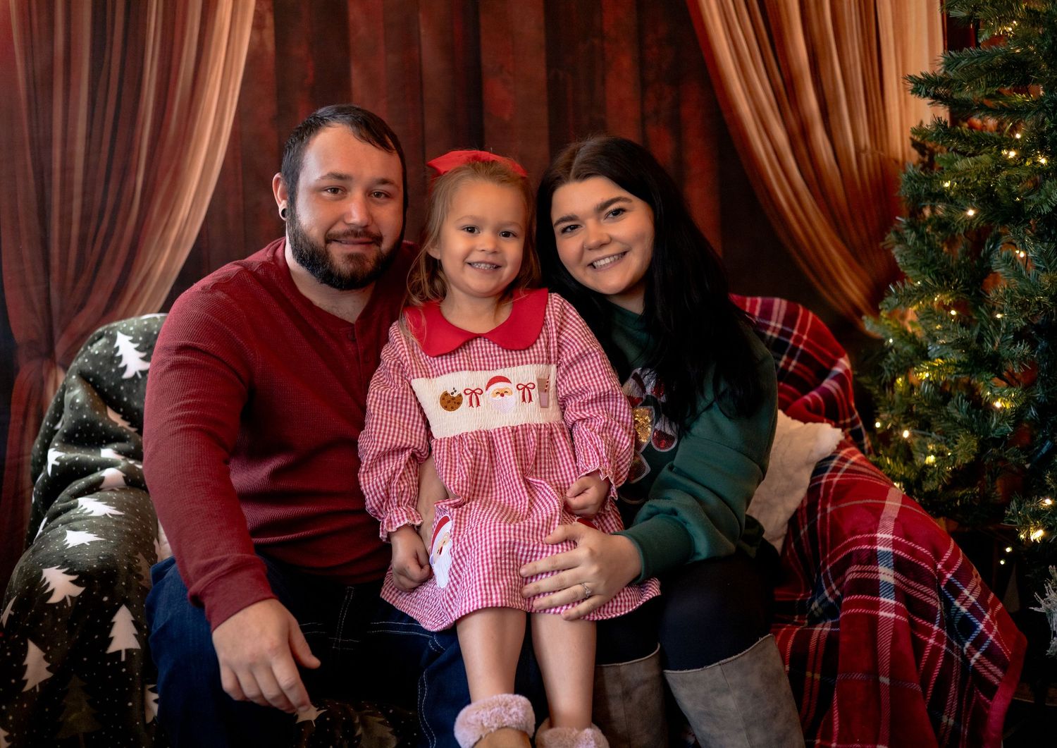 A Christmas family portrait with red and green sweaters in front of a decorated tree.