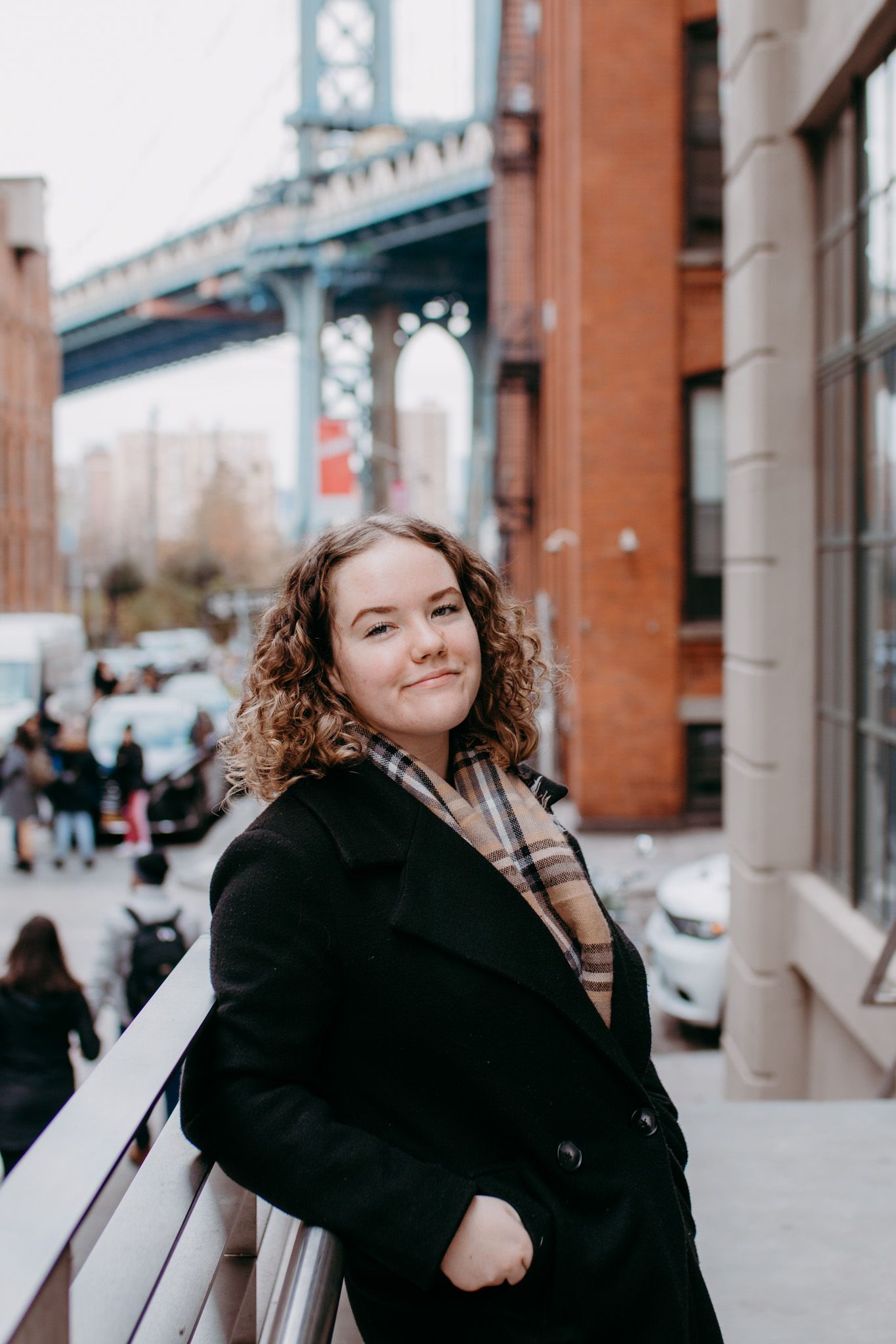 A person in winter coat poses near Manhattan Bridge in DUMBO Brooklyn.