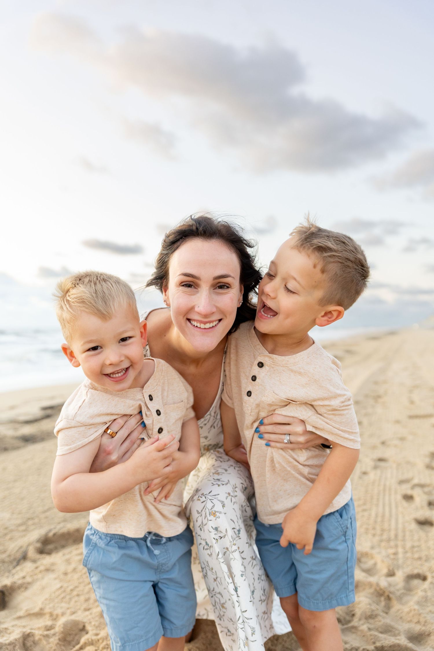 A joyful family moment captured on a sandy beach at sunset with matching outfits and natural smiles.