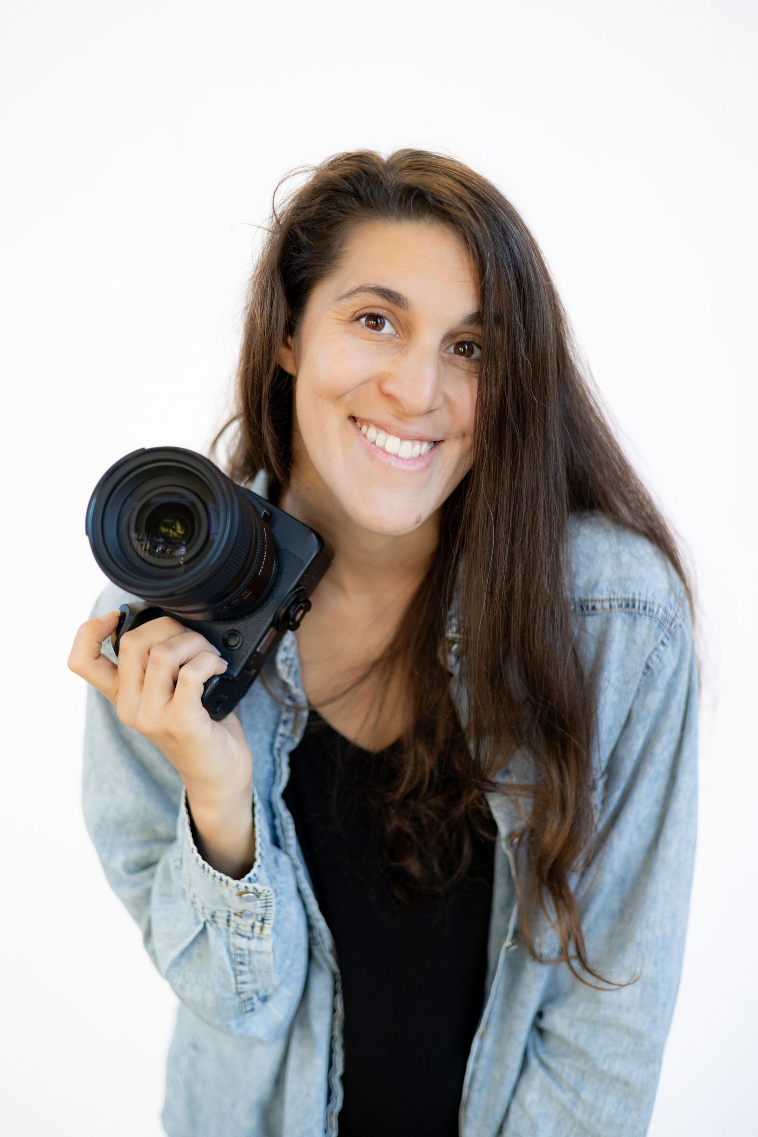 Photographer in light denim jacket and black shirt poses with camera lens in three similar expressions.