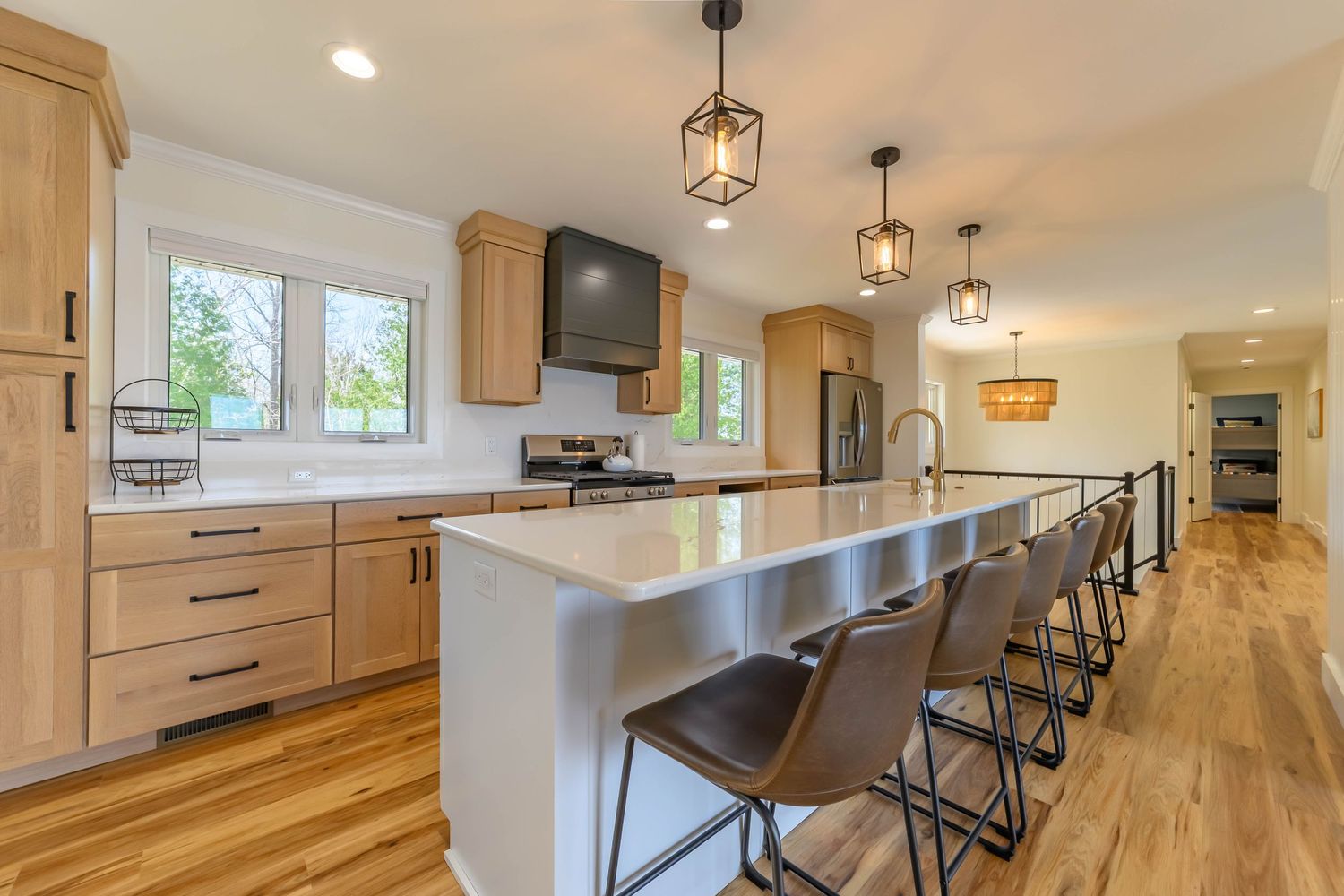 Bright modern kitchen featuring light wood cabinetry, stainless steel island countertop, pendant lighting, and hardwood floors.