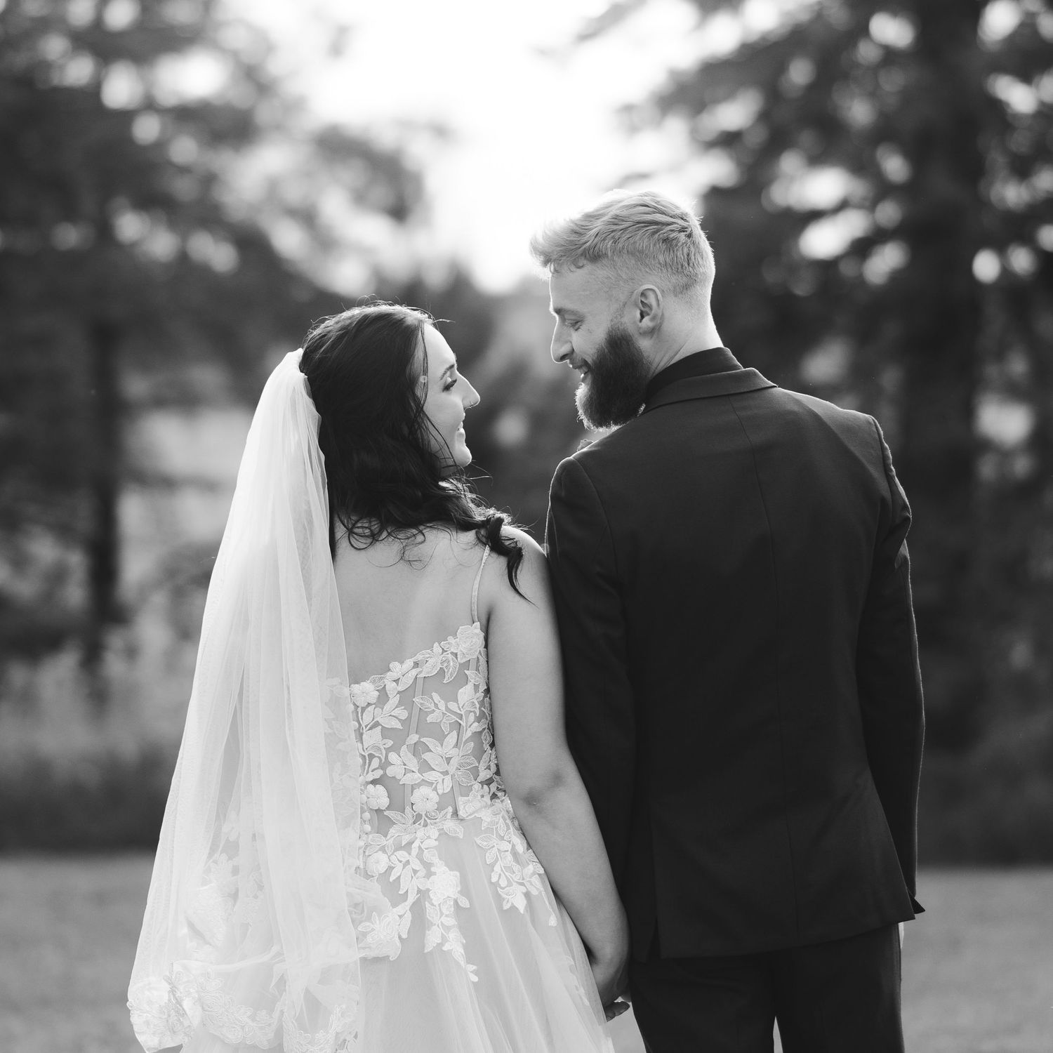 Black and white photo of bride and groom walking together outdoors after wedding.