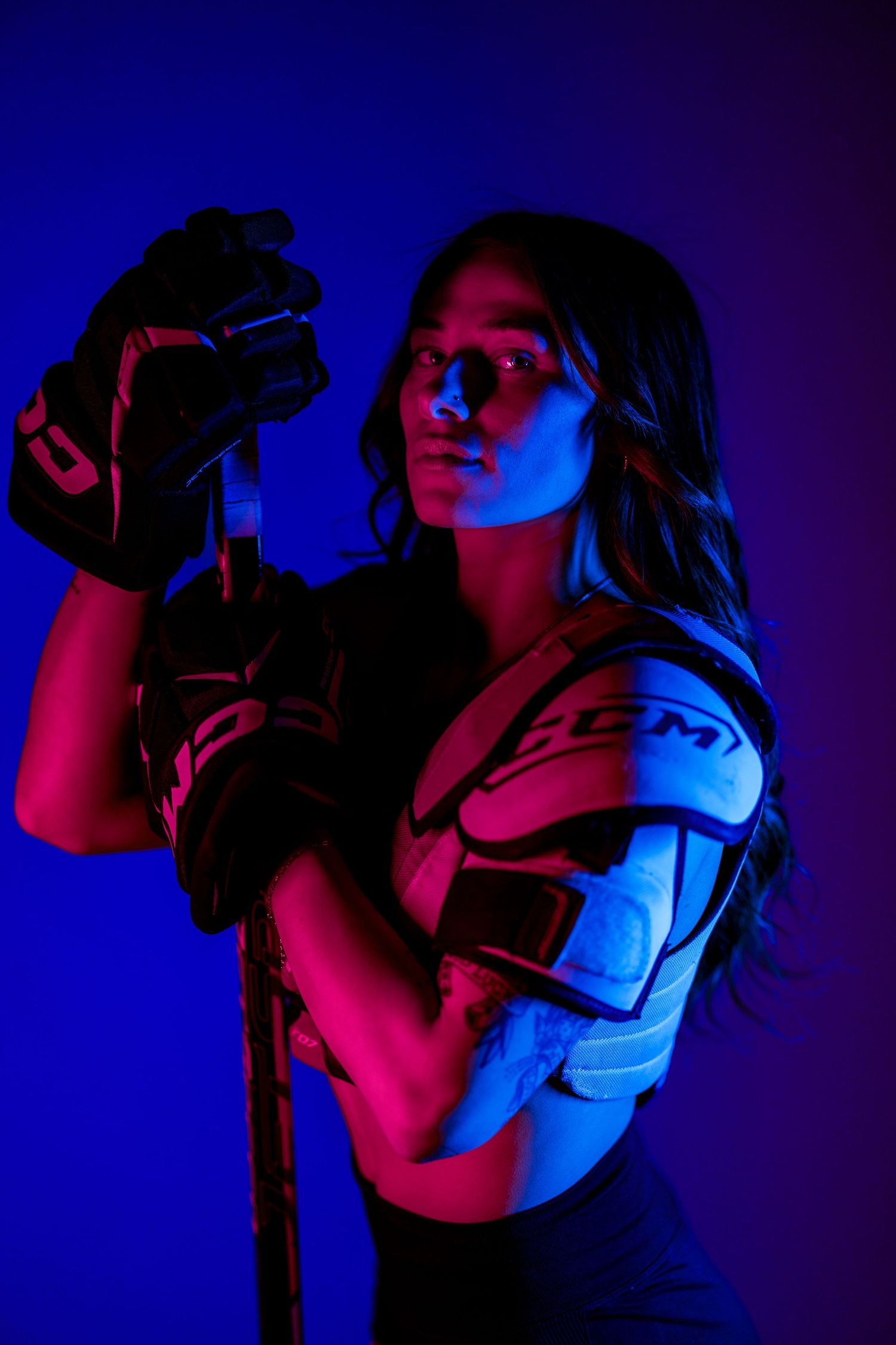 Person using virtual reality headset illuminated by dramatic blue and pink lighting in a dark environment.