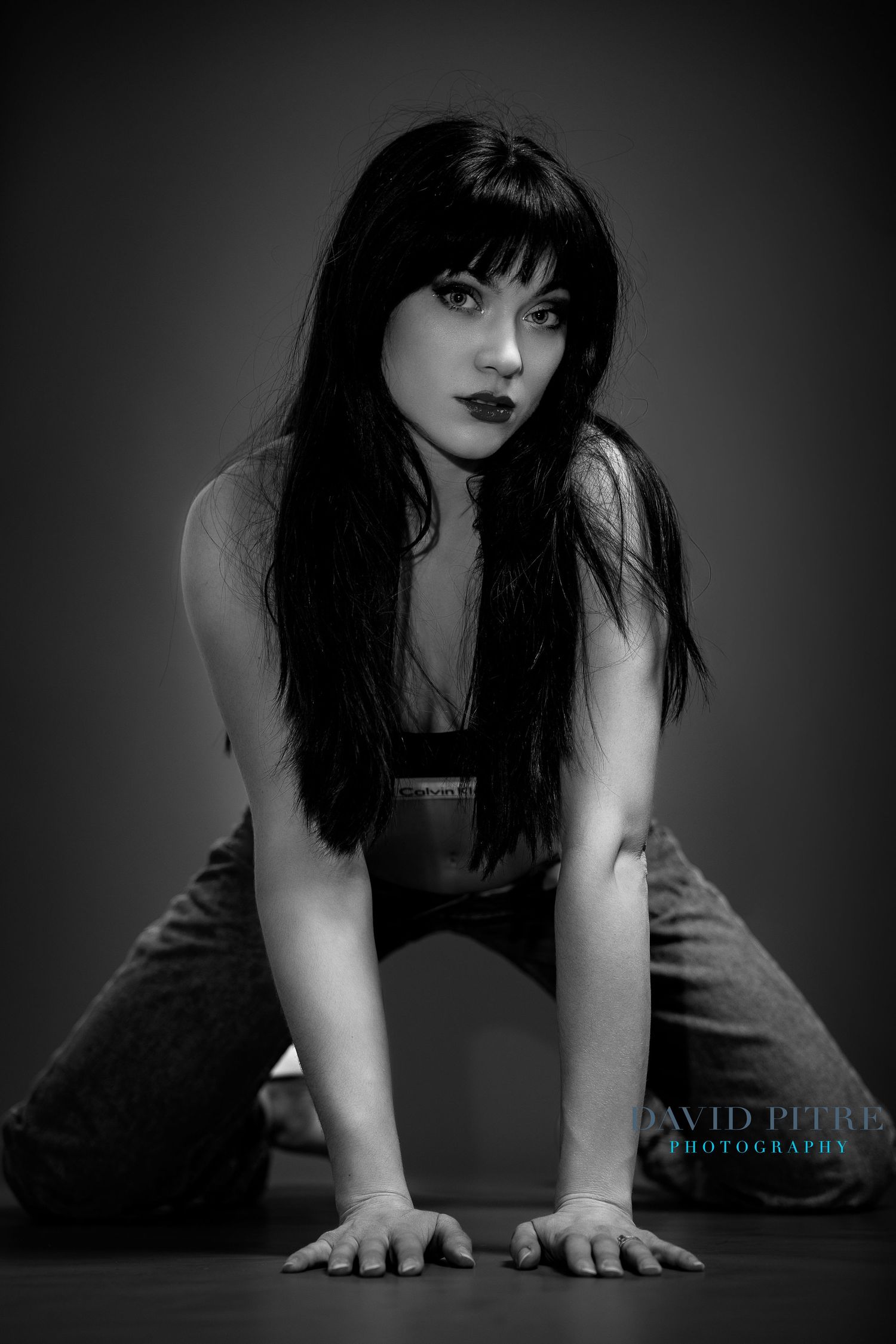 Black and white artistic portrait of a woman with long dark hair in dramatic lighting, photographed by David Pitts.