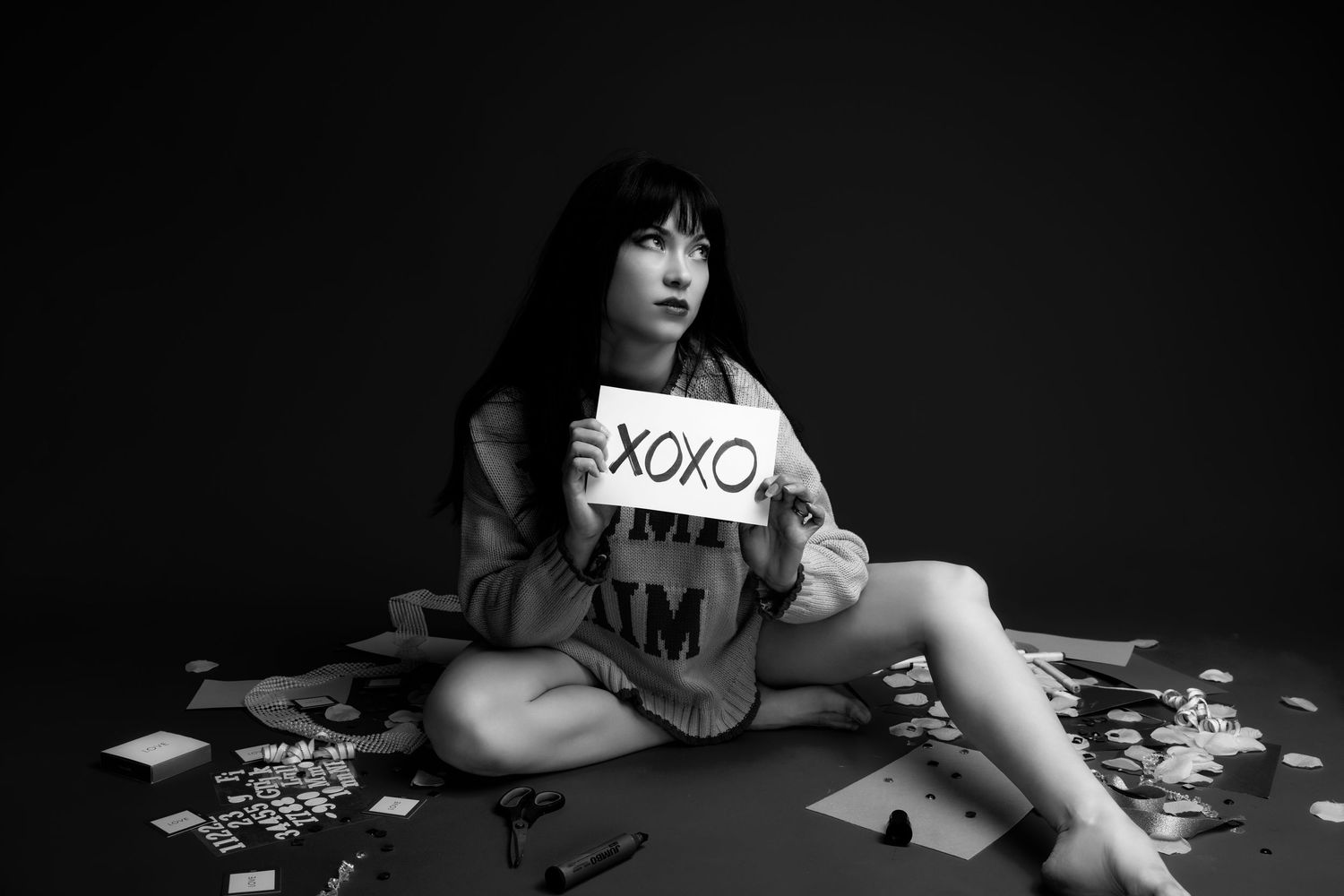 A dramatic black and white photo series showing hands and arms scattered with playing cards on a dark surface.