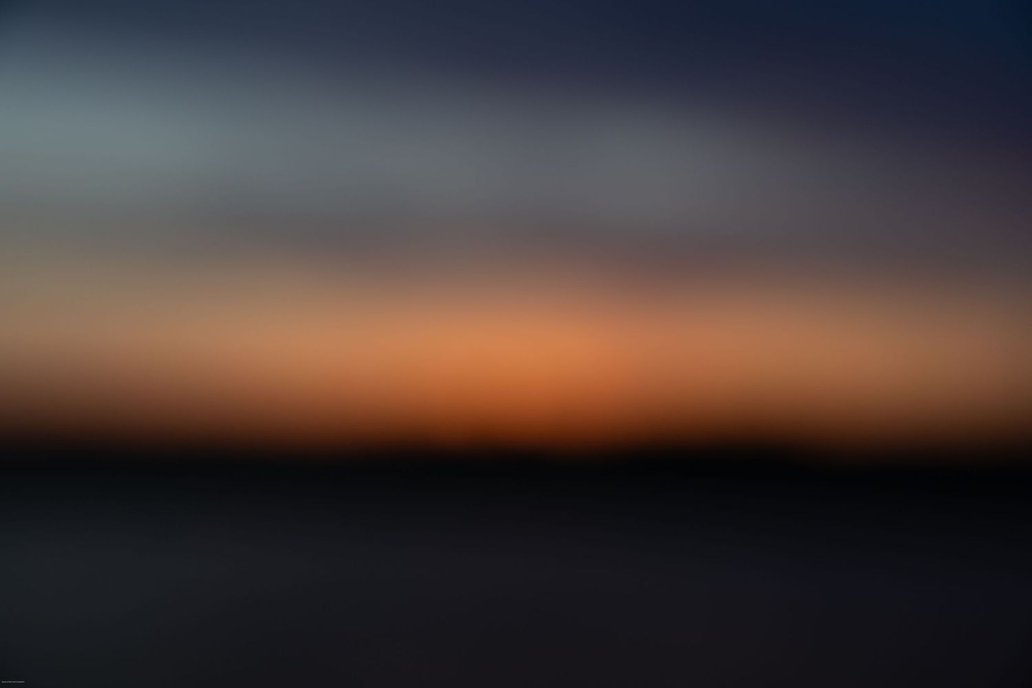 Dramatic panoramic view of a dark sky at sunset with vibrant orange and purple hues on the horizon.