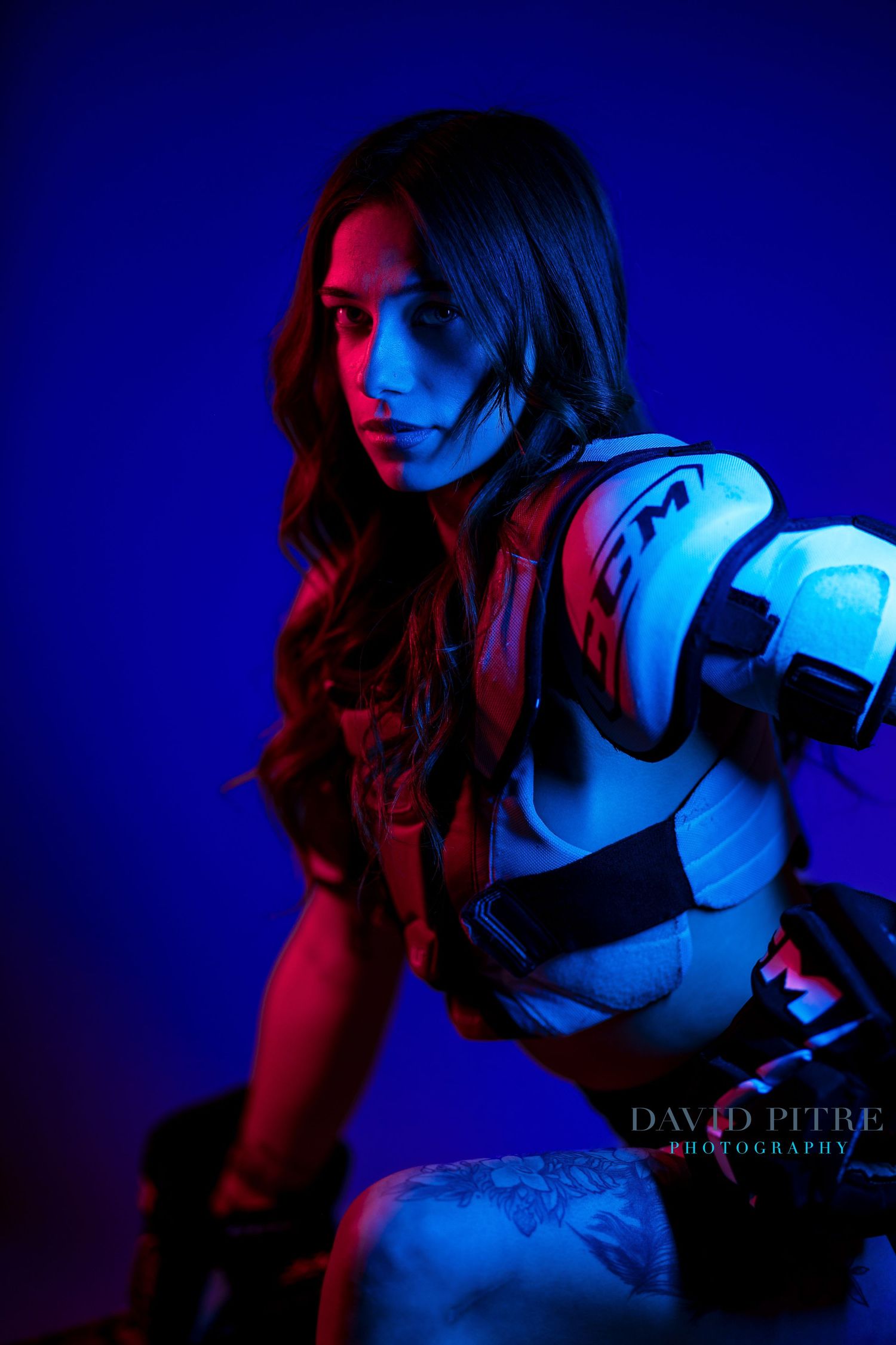 Dramatic portrait with red and blue lighting creating moody contrast against a dark background.
