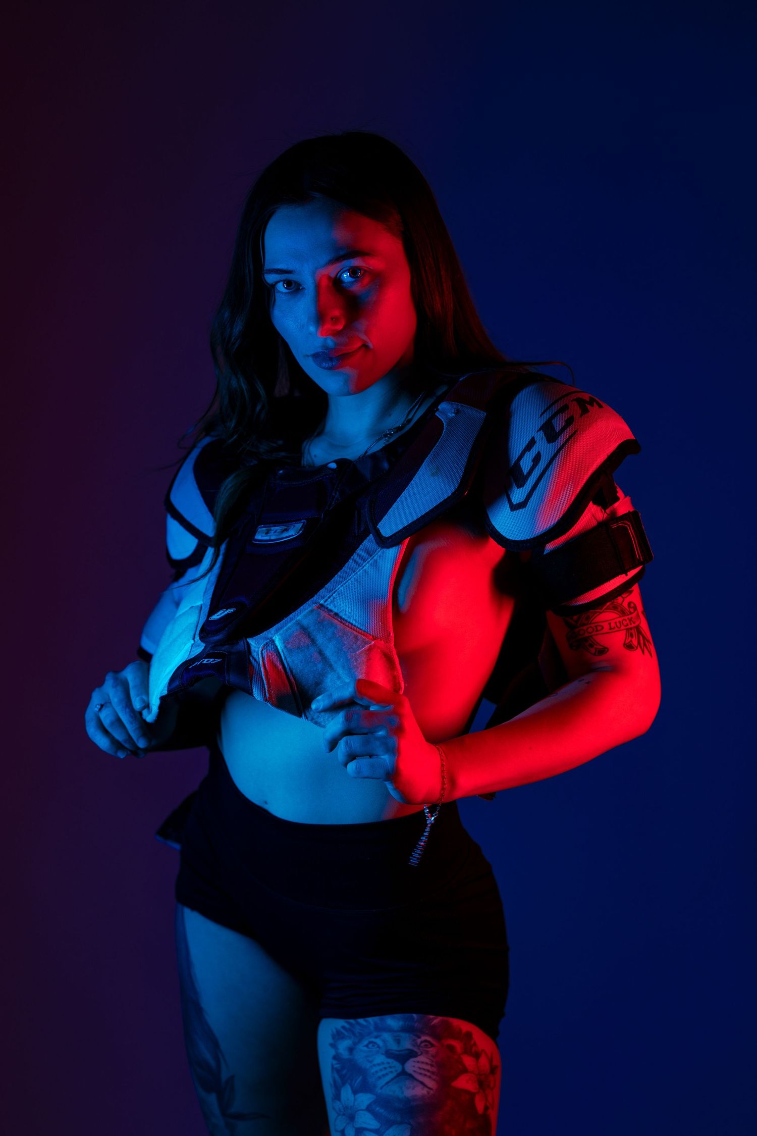 Dramatic portrait with red and blue lighting showing a person in athletic wear against a dark background.